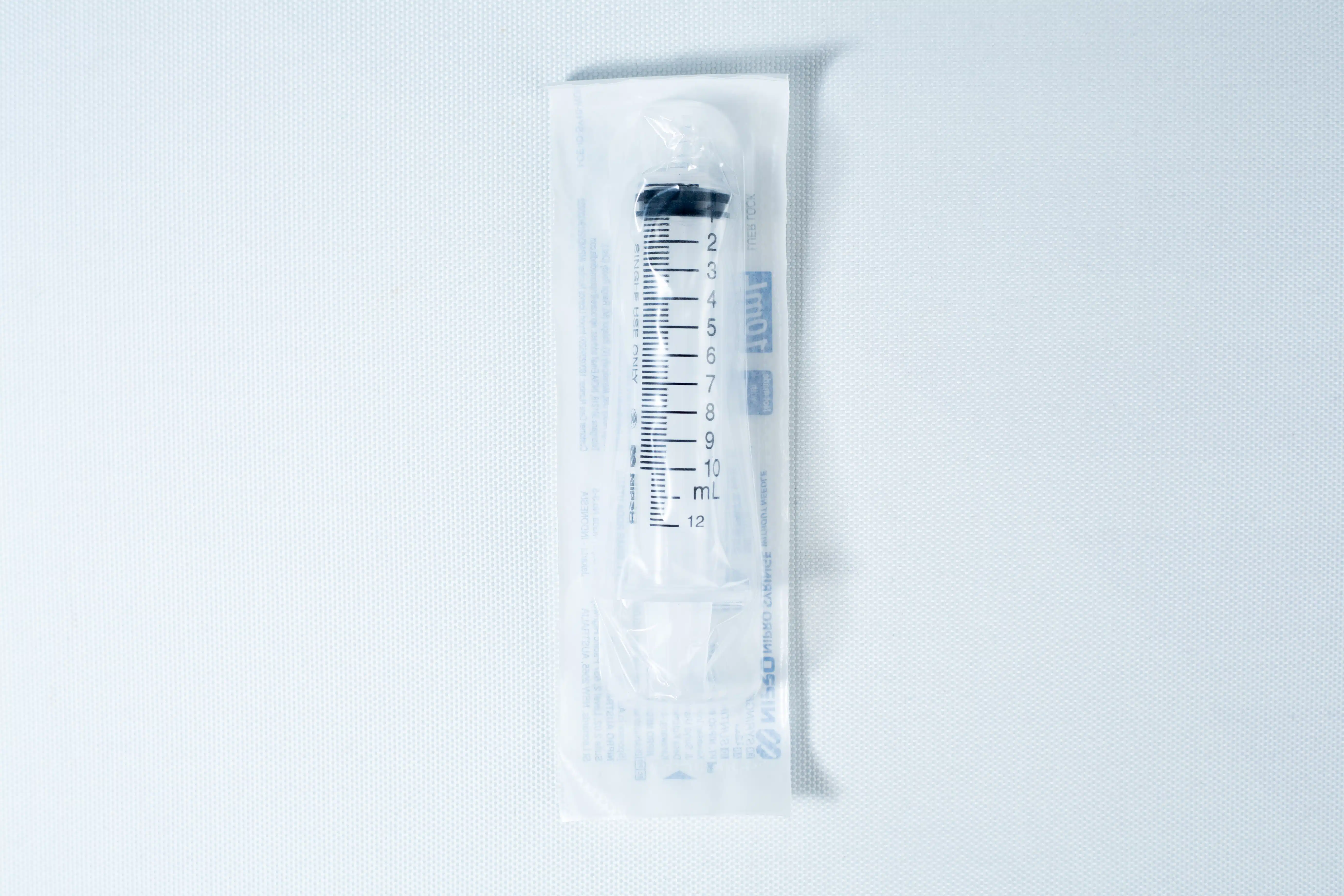 A sealed, sterile syringe in clear plastic packaging on a white surface.