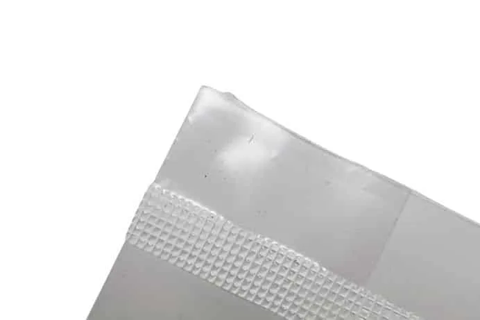 Close-up of the corner of a clear plastic bag with a textured sealing strip on a white background.