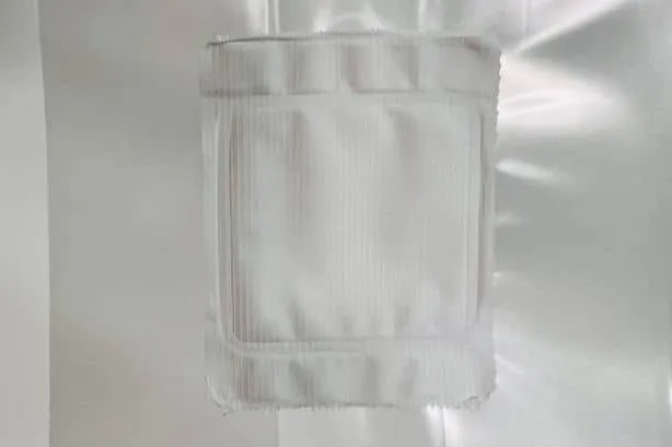 A white, square gauze pad is attached to a white, shiny surface.