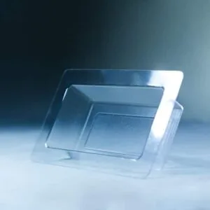 A Mycelium Mould Growth form -Brick (Reusable) stands upright on a smooth, misty surface, its organic curves reflected in the transparent plastic food container lid beside it.