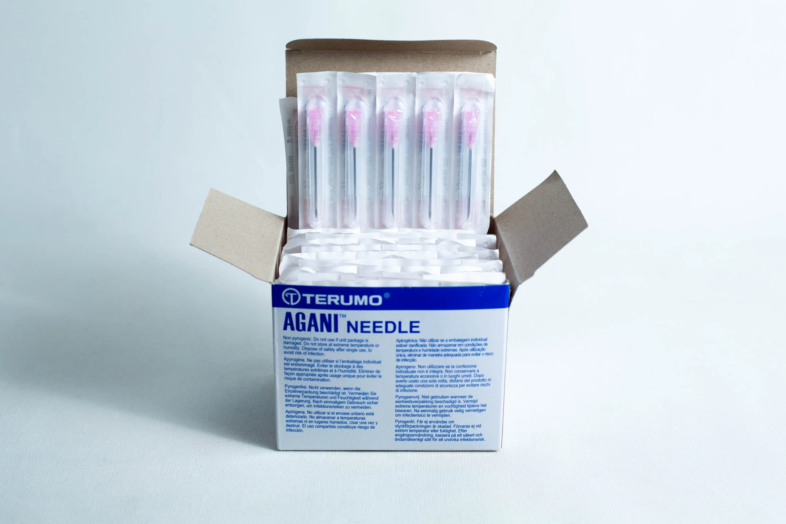 Open box of sterile 18G hypodermic needles whole box 100pcs, showing several individually wrapped sterile needles inside.