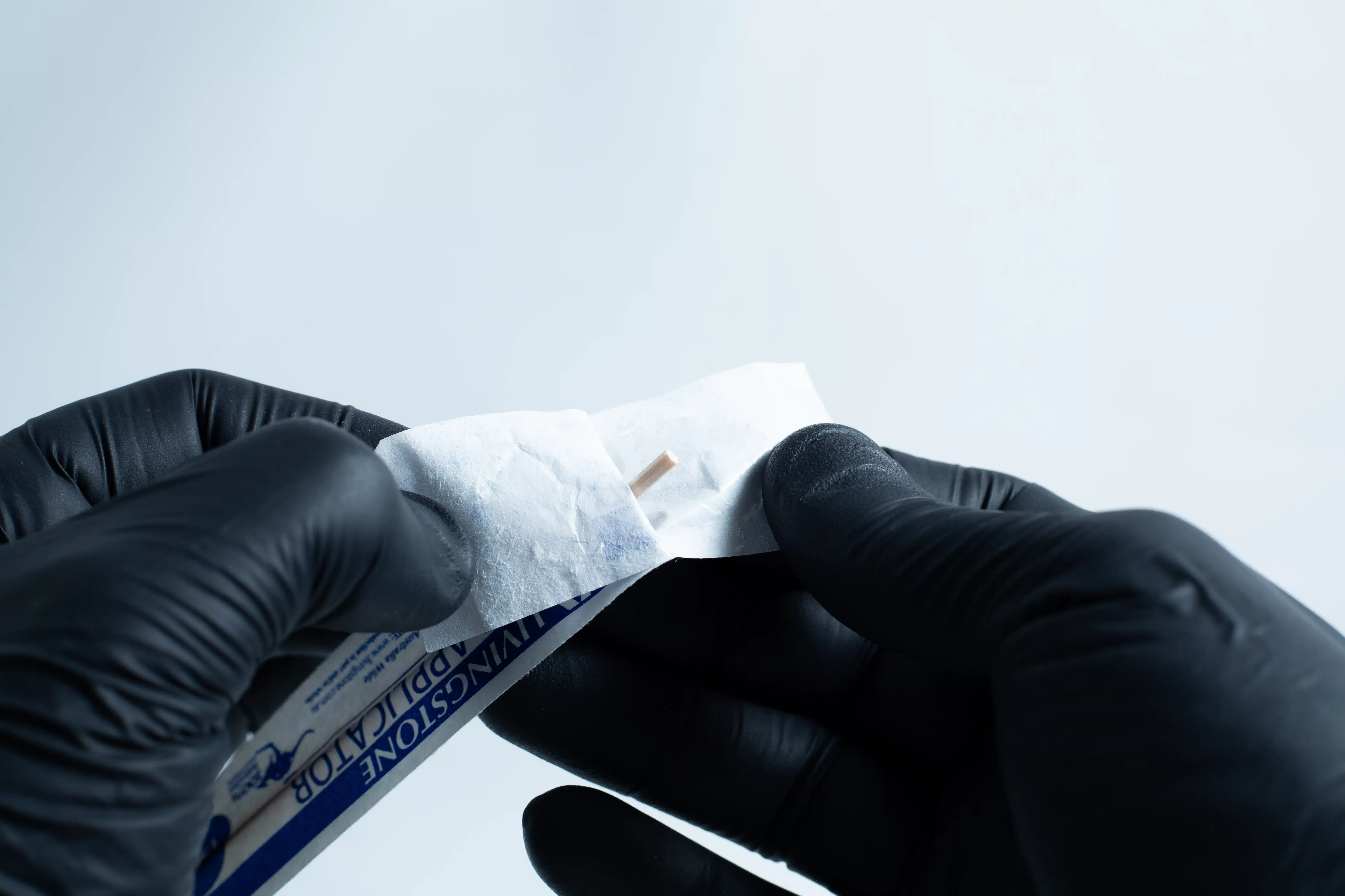 Gloved hands open an antiseptic wipe packet against a plain background, preparing the agar Petri dish MEA School Science Fun Project Kit for a school science activity.