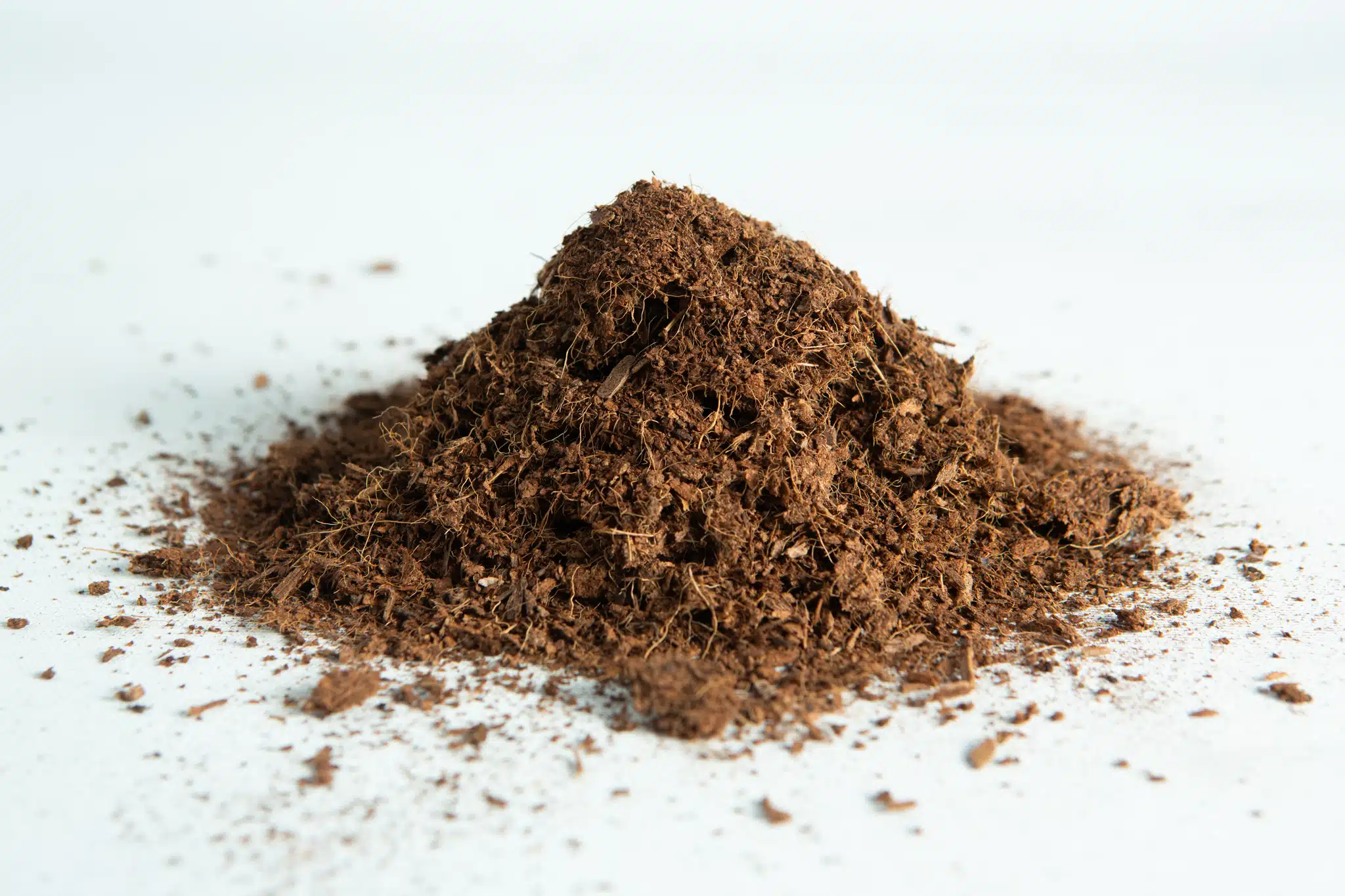 A small pile of coco coir block 5 kg, 60L, washed of salts buffered RHP grade on a white surface.