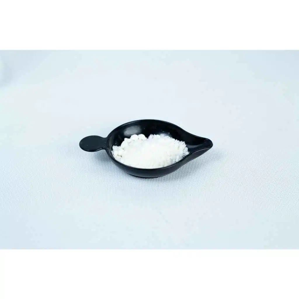 A small black dish holds Antibacterial Powder for mushroom cultivation, seen as a fine white substance on a plain white surface.
