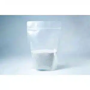 A clear resealable pouch containing white coarse Natural Gypsum mushroom supplement grain and substrate stands on a light backgroundโperfect for storage and use.