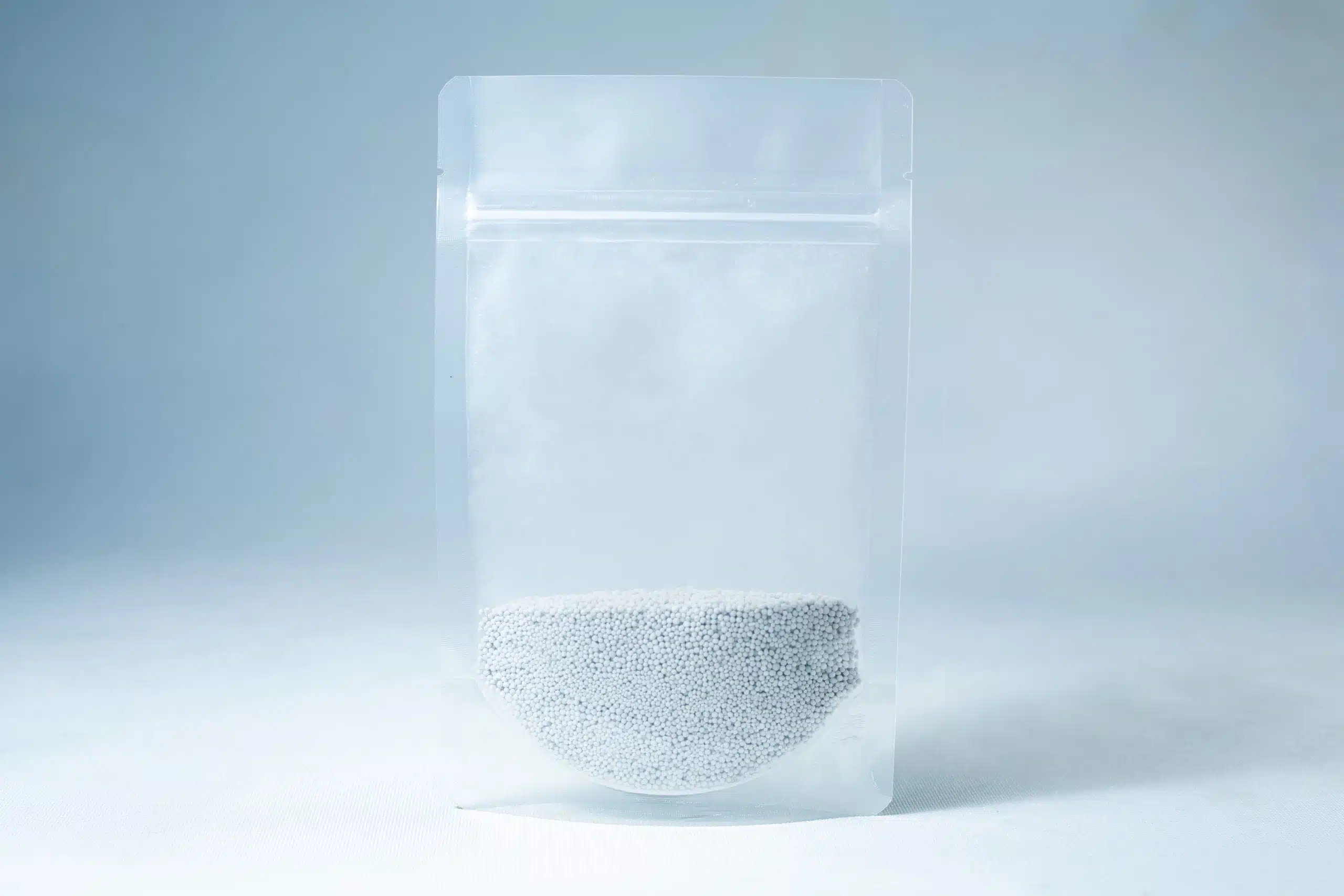 A clear resealable bag containing small white Natural Gypsum coarse grade pellets, used as a mushroom supplement for grain and substrate, is shown on a light blue background.