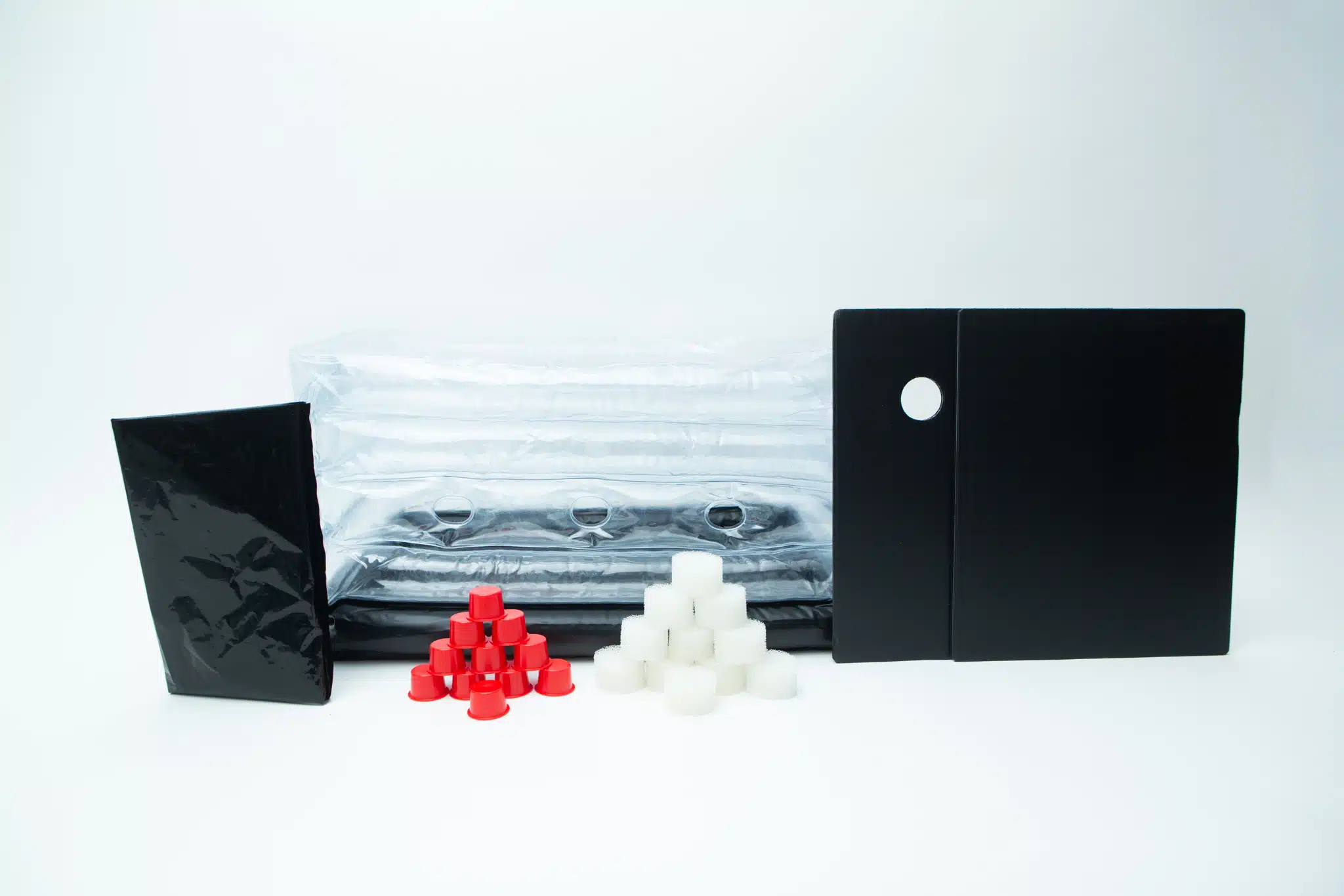 Assorted black, red, and white plastic parts and sheets arranged on a white background—perfect components for assembling your Inflatable monotub kit for Growing mushrooms – Boomer Shroomer V 2.0.