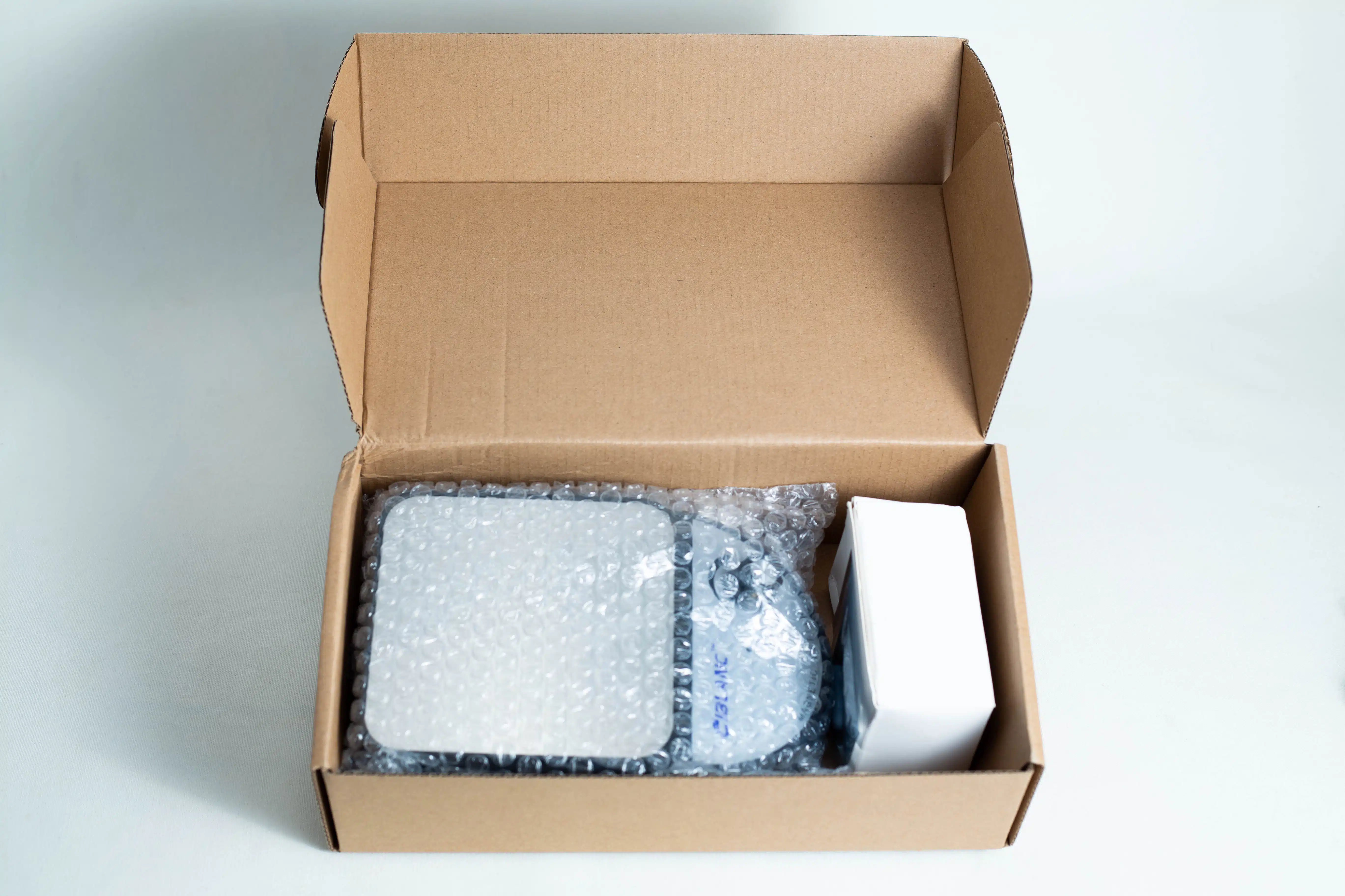 Magnetic Stirrer machine 3500rpm 4 Open cardboard box with bubble-wrapped items and a white rectangular box inside, possibly containing the Magnetic Stirrer Ciblanc 3500rpmโideal for anyone seeking magnetic stirrer equipment. All items are neatly arranged on a white surface.
