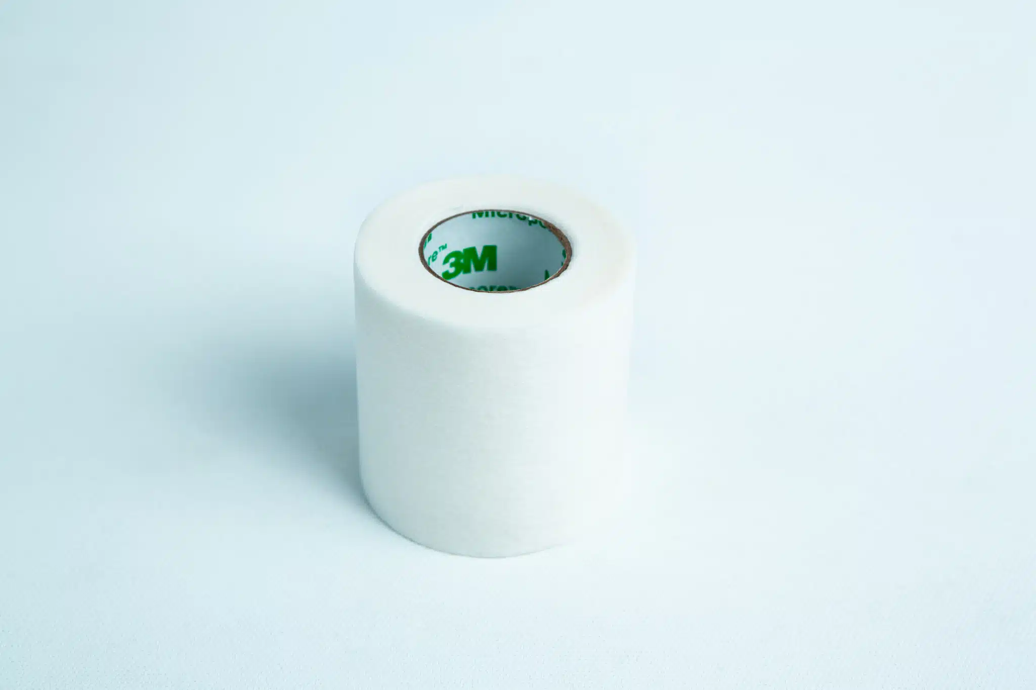 A roll of Micropore tape Mycology autoclavable breathable rests on a light blue background, ready for gentle and secure medical use.