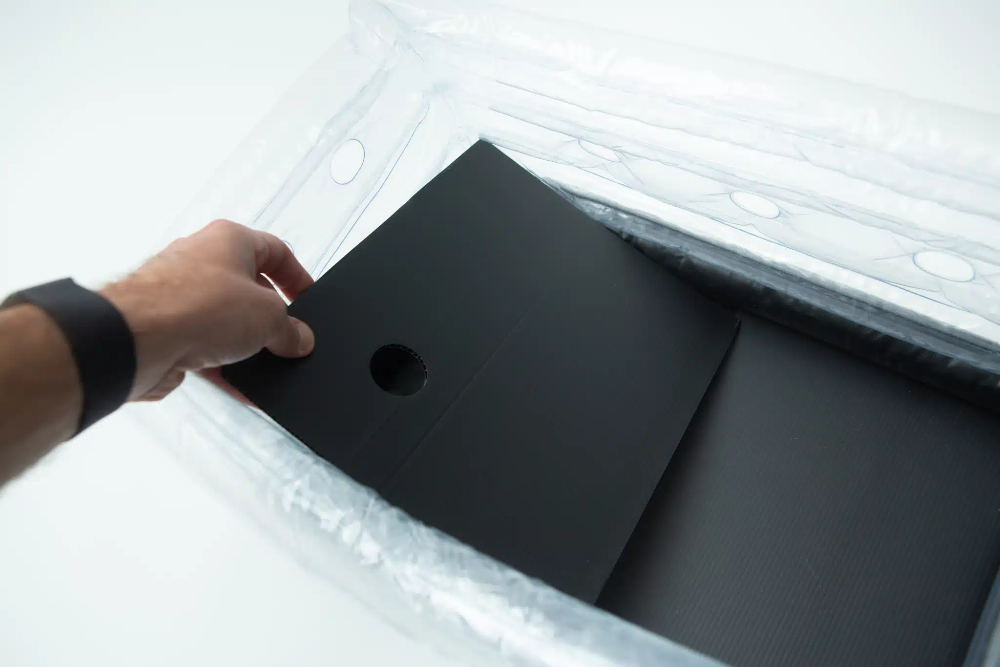 A hand places a black sheet with a hole into the Boomer Shroomer V 2.0 inflatable monotub kit for growing mushrooms.