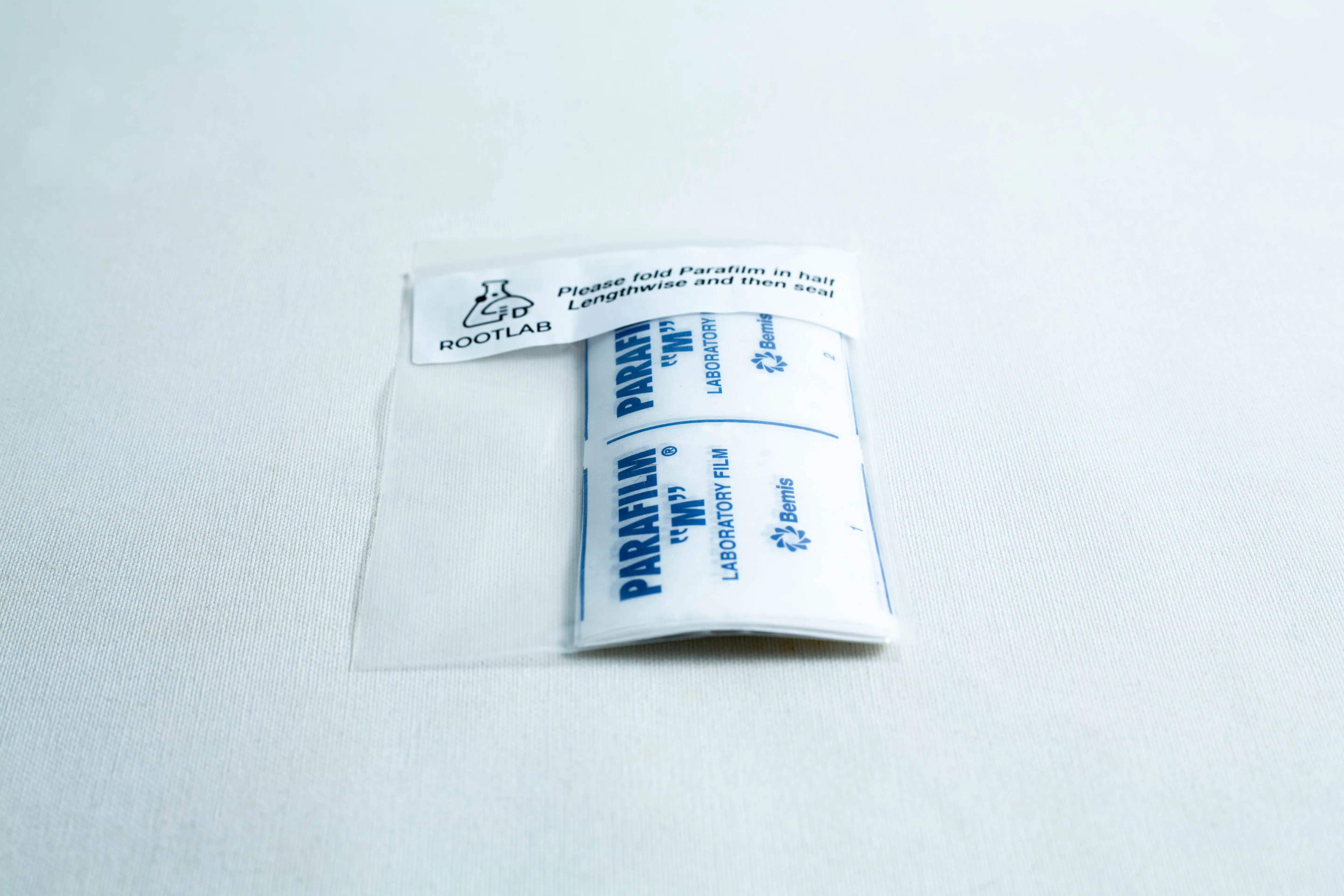 A packet of Pre-cut Parafilm strips 10x Lab cut film in clear packaging displayed on a white surface.