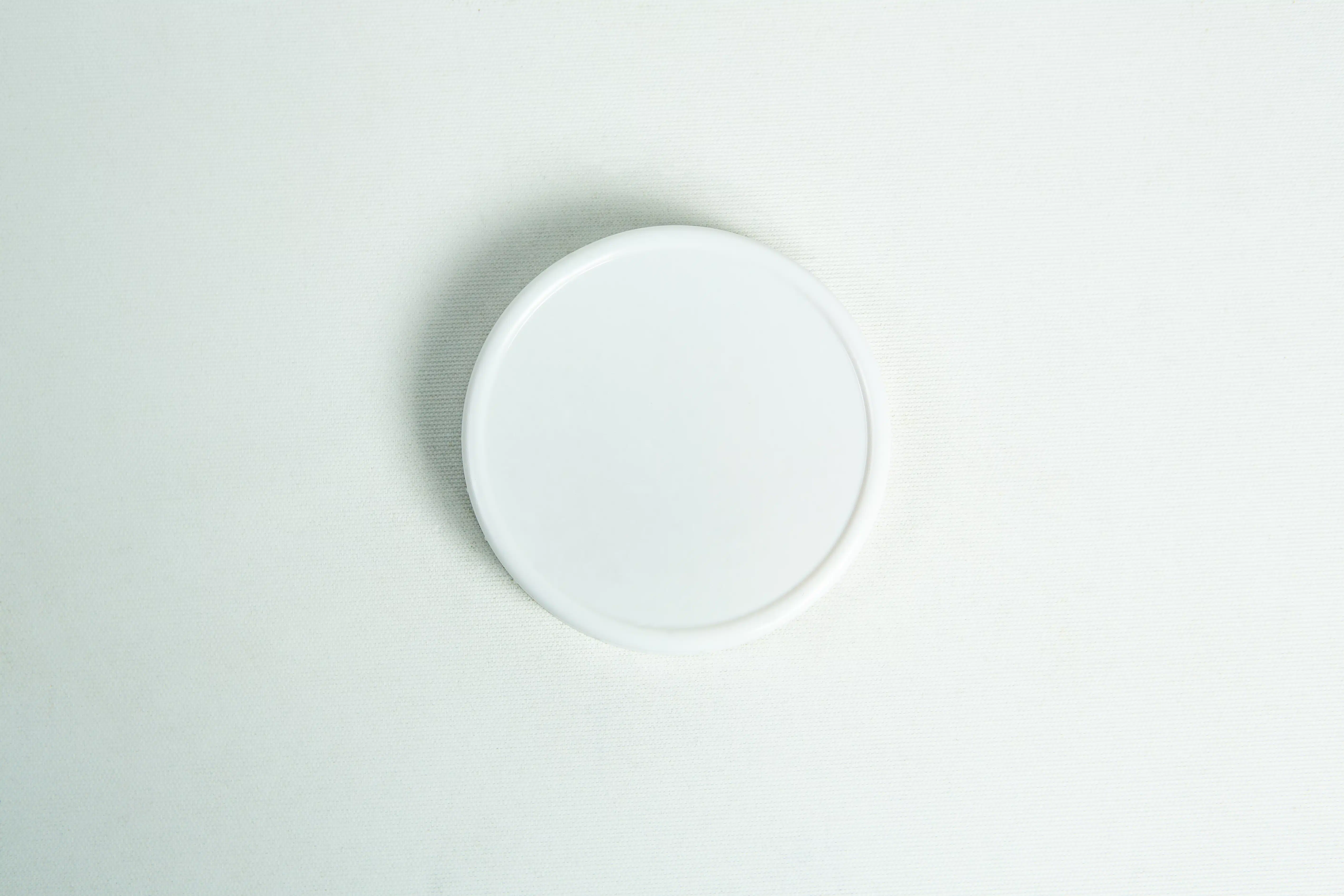 Mason Jar Lids | Wide mouth 86mm | Plain White Plastic Lids 4 A plain white, wide-mouth 86mm plastic Mason jar lid rests on a simple white surface.