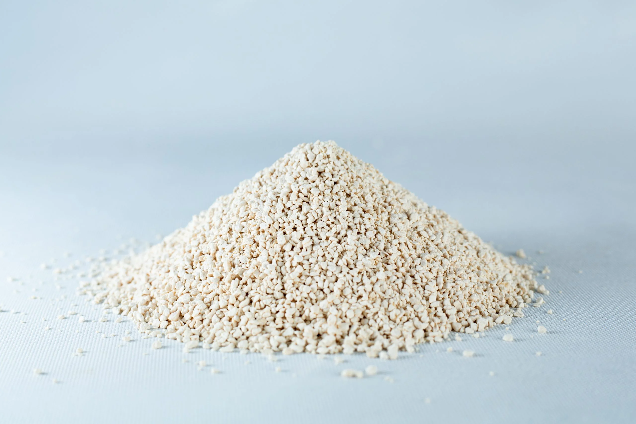 Potato Dextrose Agar powder -Lab Grade 2 A small mound of Natural Gypsum coarse grade mushroom supplement grain and substrate, featuring beige, granular powder, rests on a light grey surface.