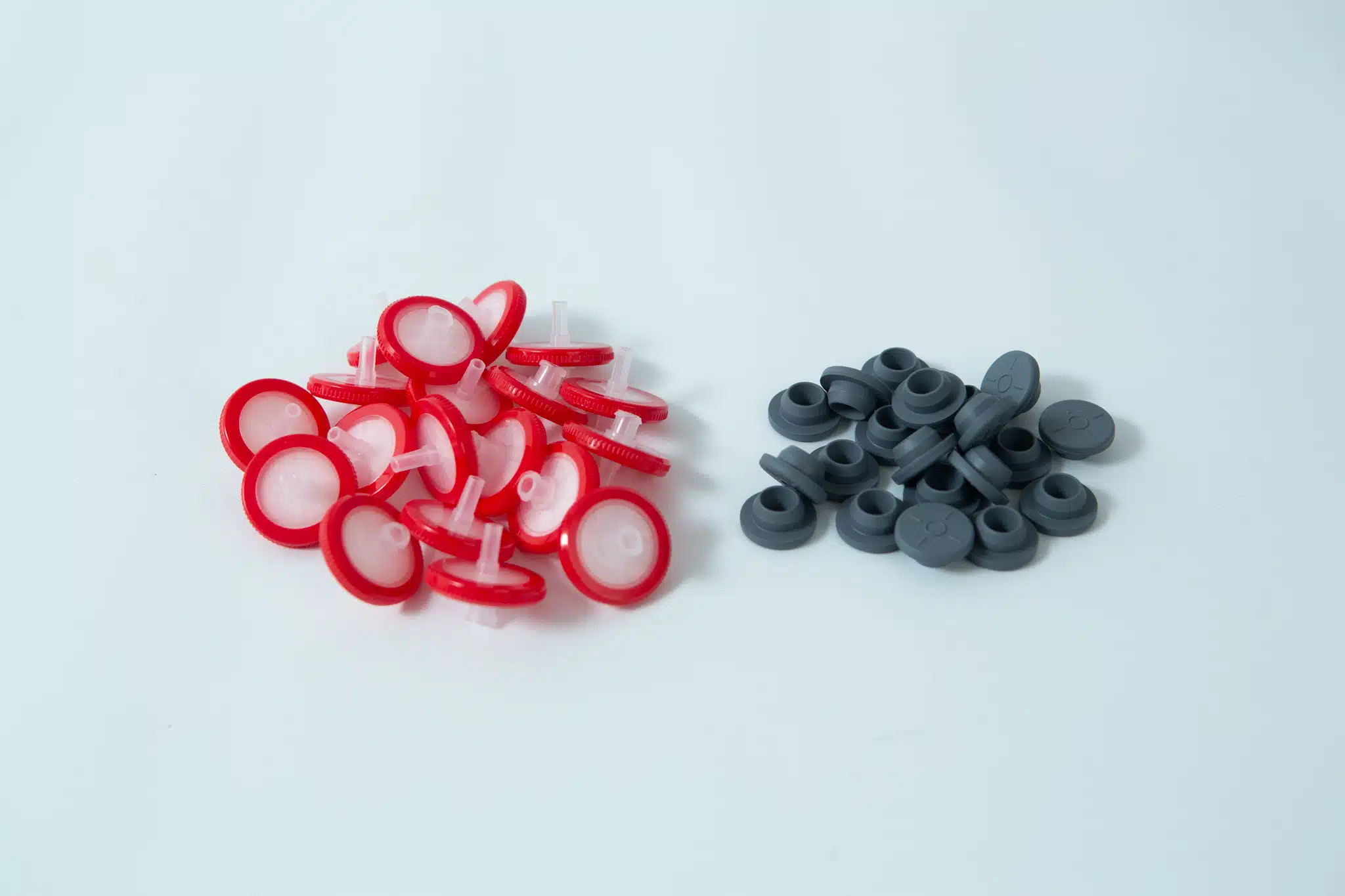 A set of Rubber Self-Healing Injection ports and red-and-white PTFE Syringe Filters for Mycology are arranged together on a white surface.