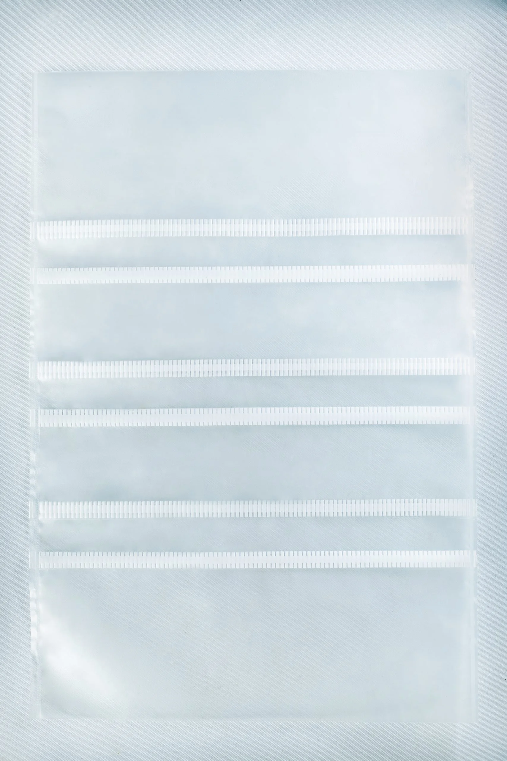 A clear plastic sheet with four horizontal pocket strips, perfect for organising supplies like Mushroom Grow Bags Unicorn for spawn and substrate or other mushroom grow bag essentials.