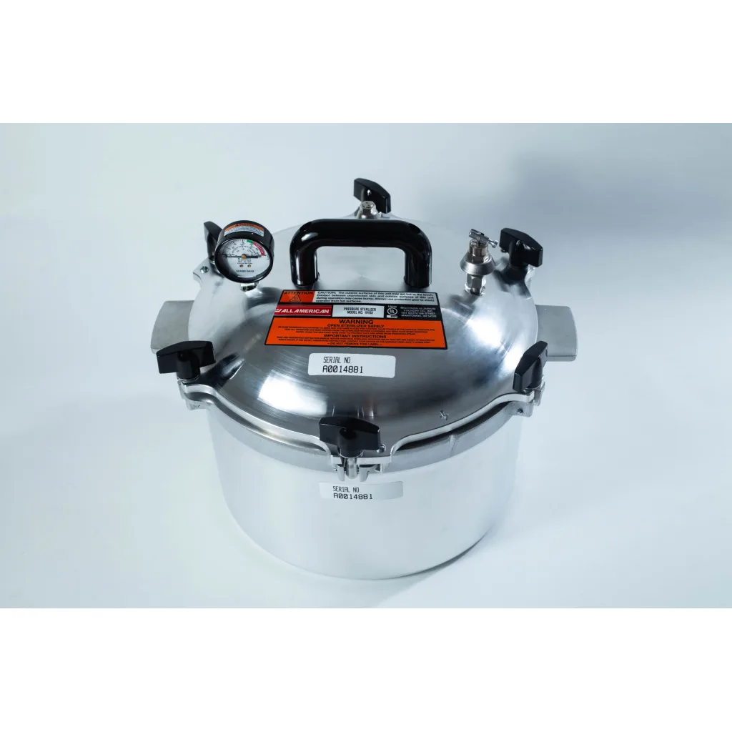 A stainless steel pressure cooker with a pressure gauge, black handles, and warning labels on the lid.