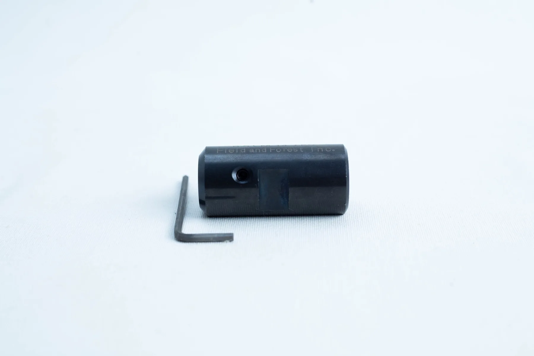 A small black cylindrical tool and an L-shaped hex key on a white background.
