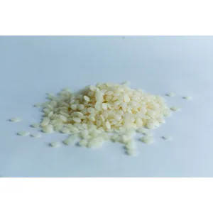 A small pile of uncooked white rice grains on a plain, light surface.