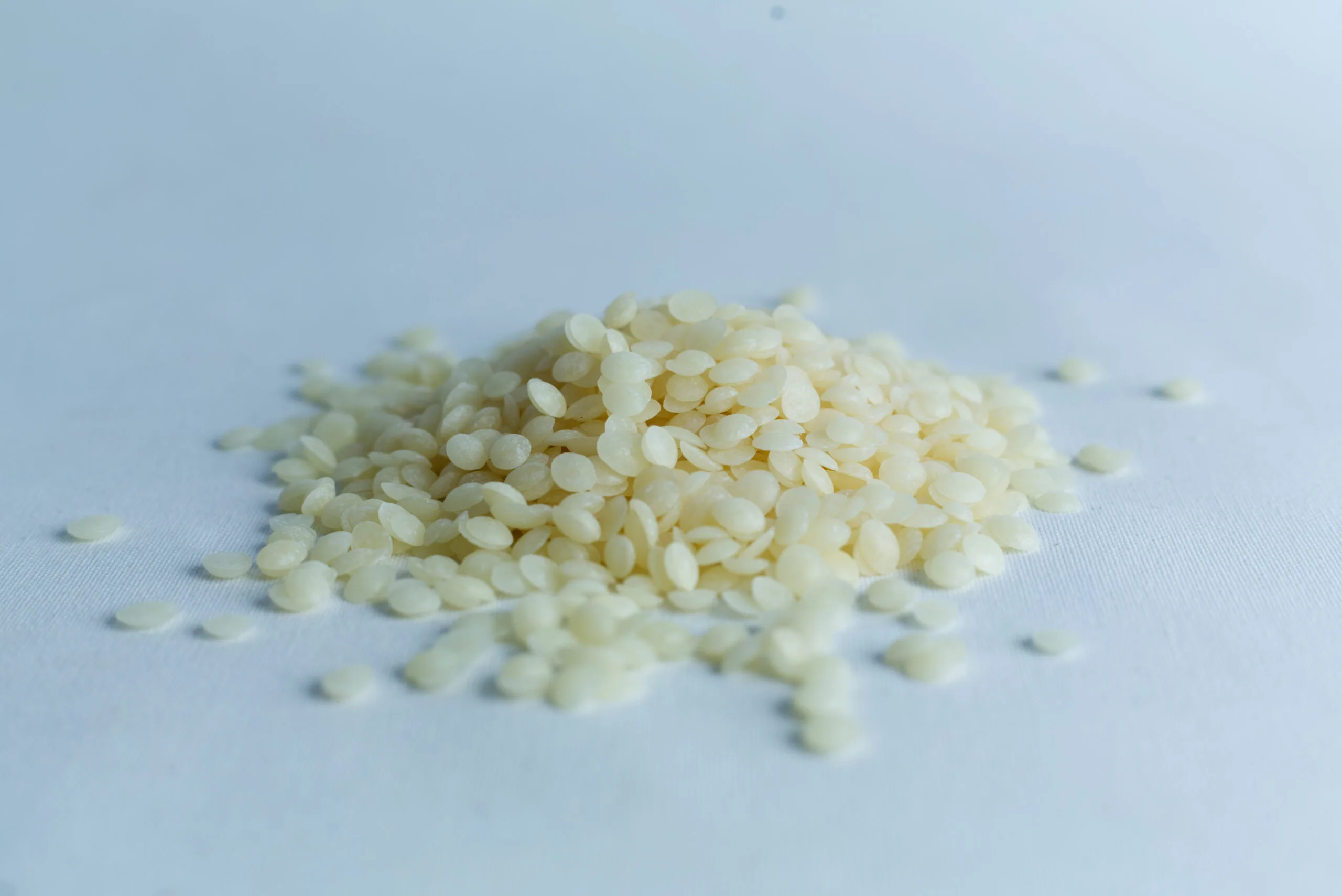 A small pile of uncooked white rice grains on a plain, light surface.