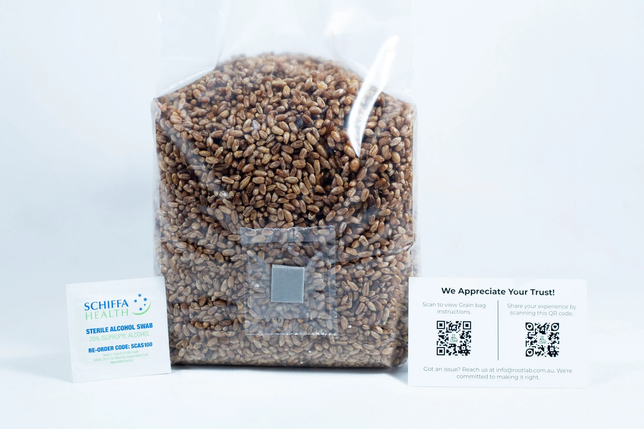 A bag of rye grain organic pre-sterilised for mushroom cultivation with injection port and air filter is placed between a business card and an appreciation card with QR codes, all on a white background.
