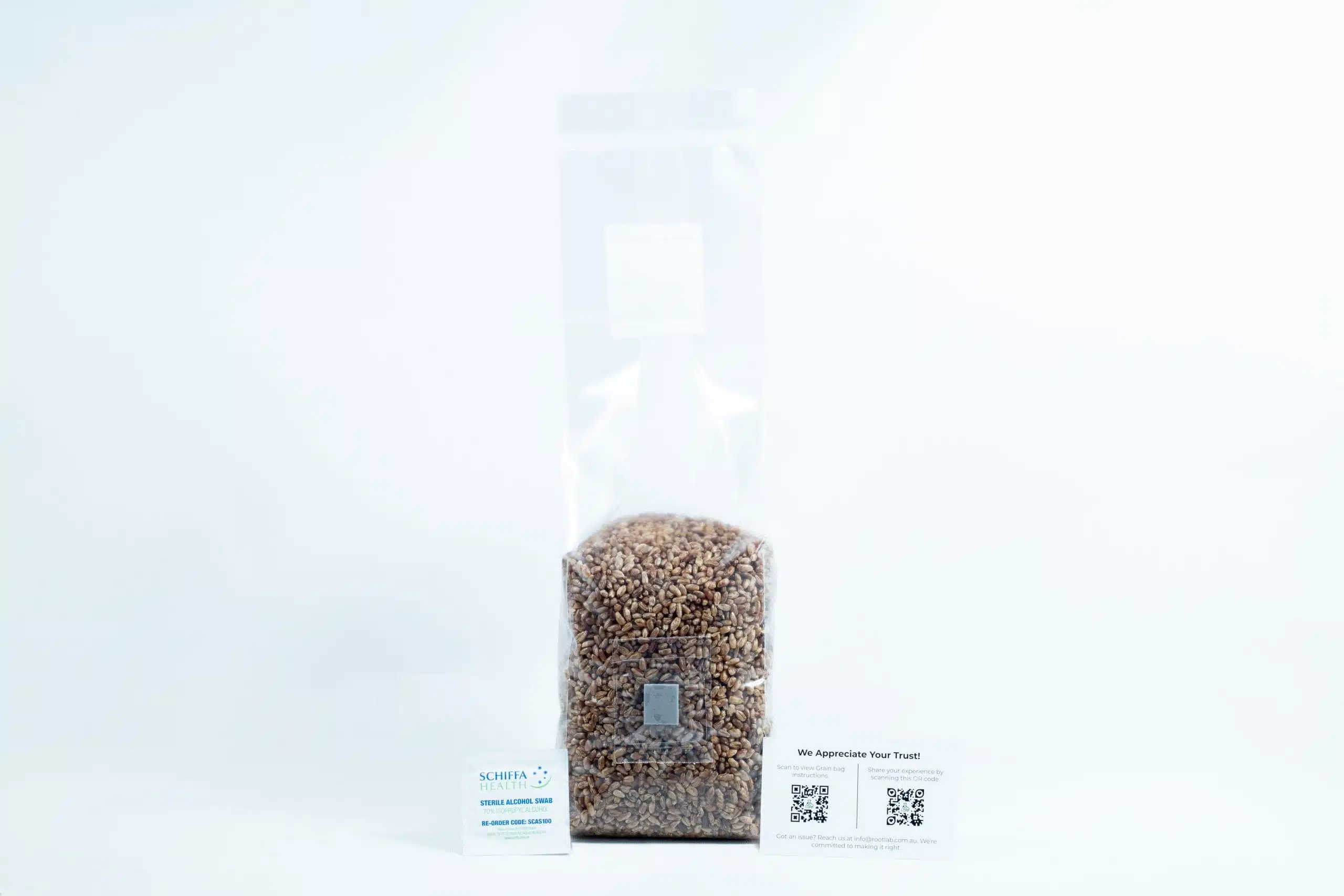 A clear bag of organic pre-sterilised rye grain for mushroom cultivation with injection port and air filter, plus two business cards in front—all on a white background.