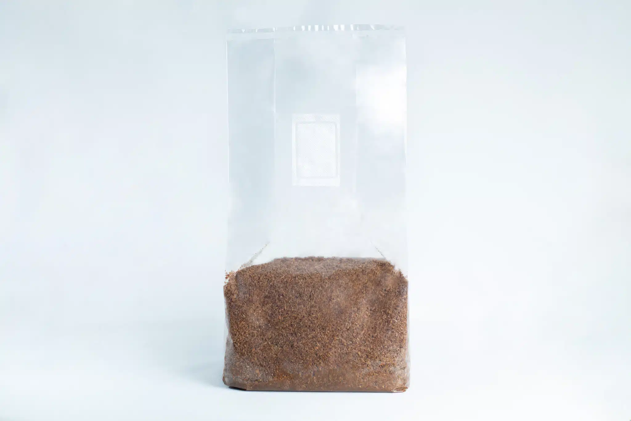 A clear plastic bag, filled halfway with brown granules of Masters Mix Mushroom Substrate Sawdust and Soya Pellets, is pictured against a white background.