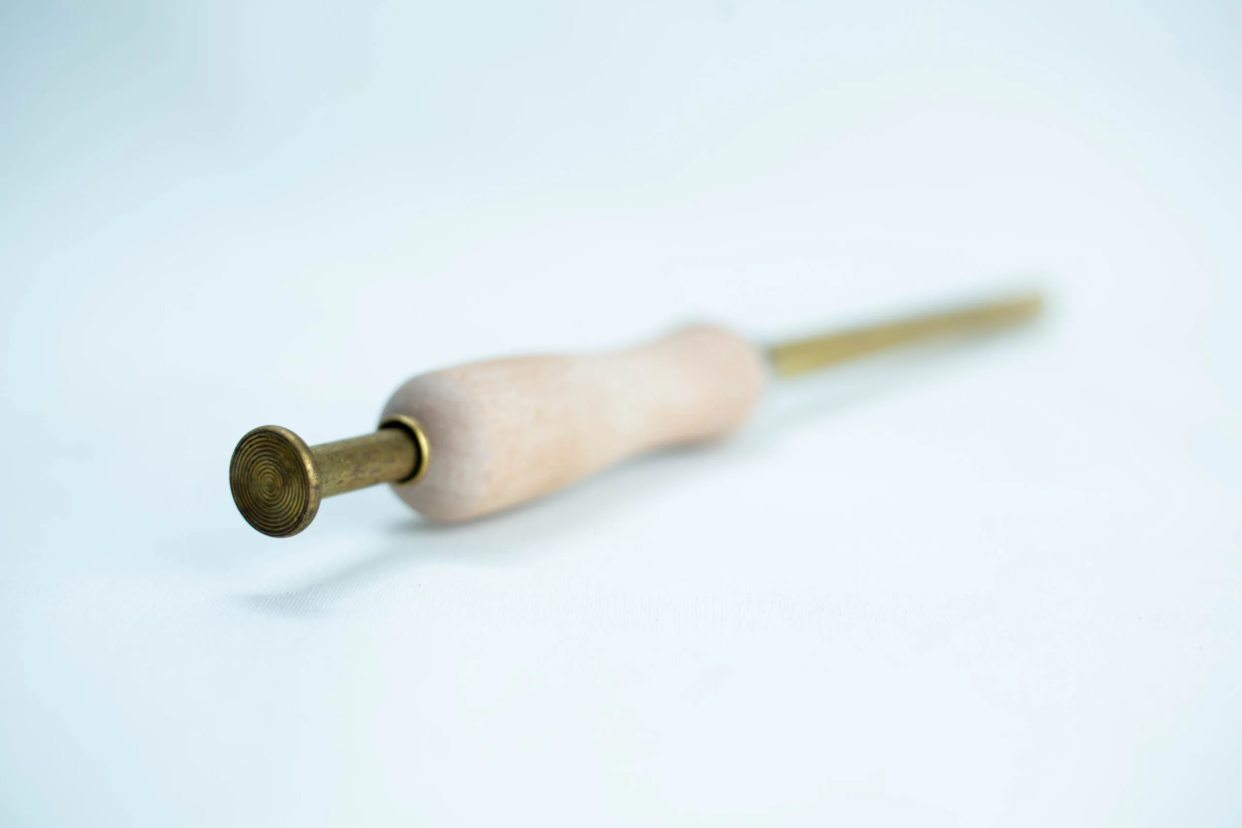Sawdust Log Inoculation Tool for 12.5mm hole 2 A brass and wooden tool with a round textured tip, lying on a white surface.
