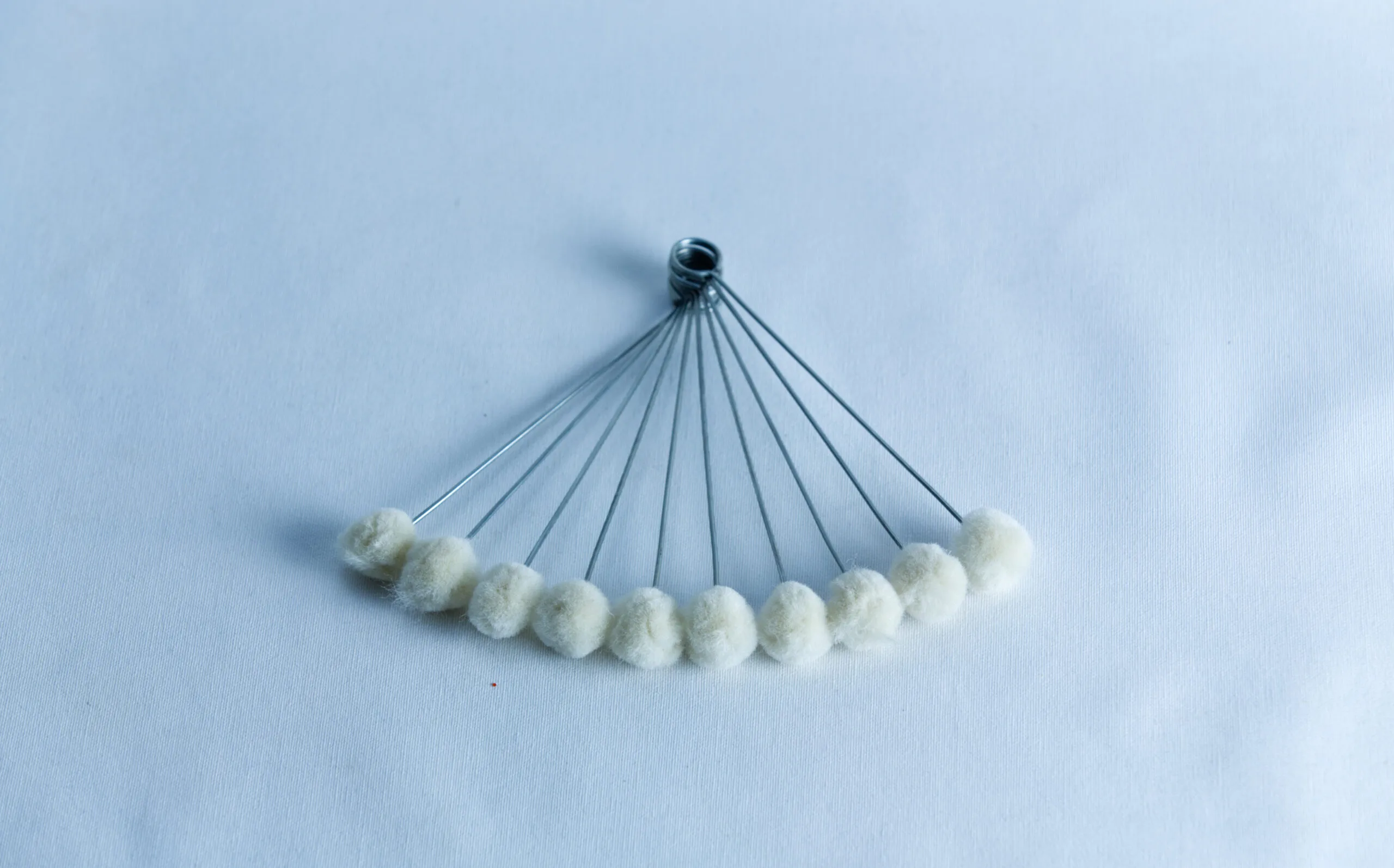 Ten metal rods with white cotton tips, arranged in a fan shape on a white background.