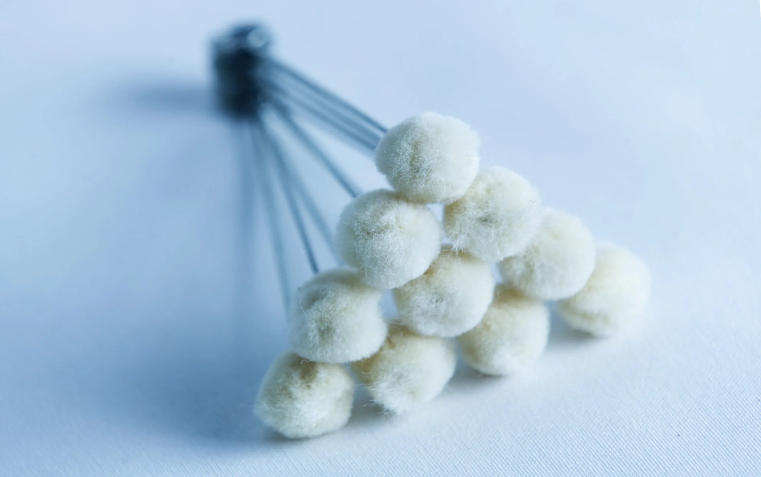 A cluster of white cotton buds arranged in a triangular formation on a light surface.