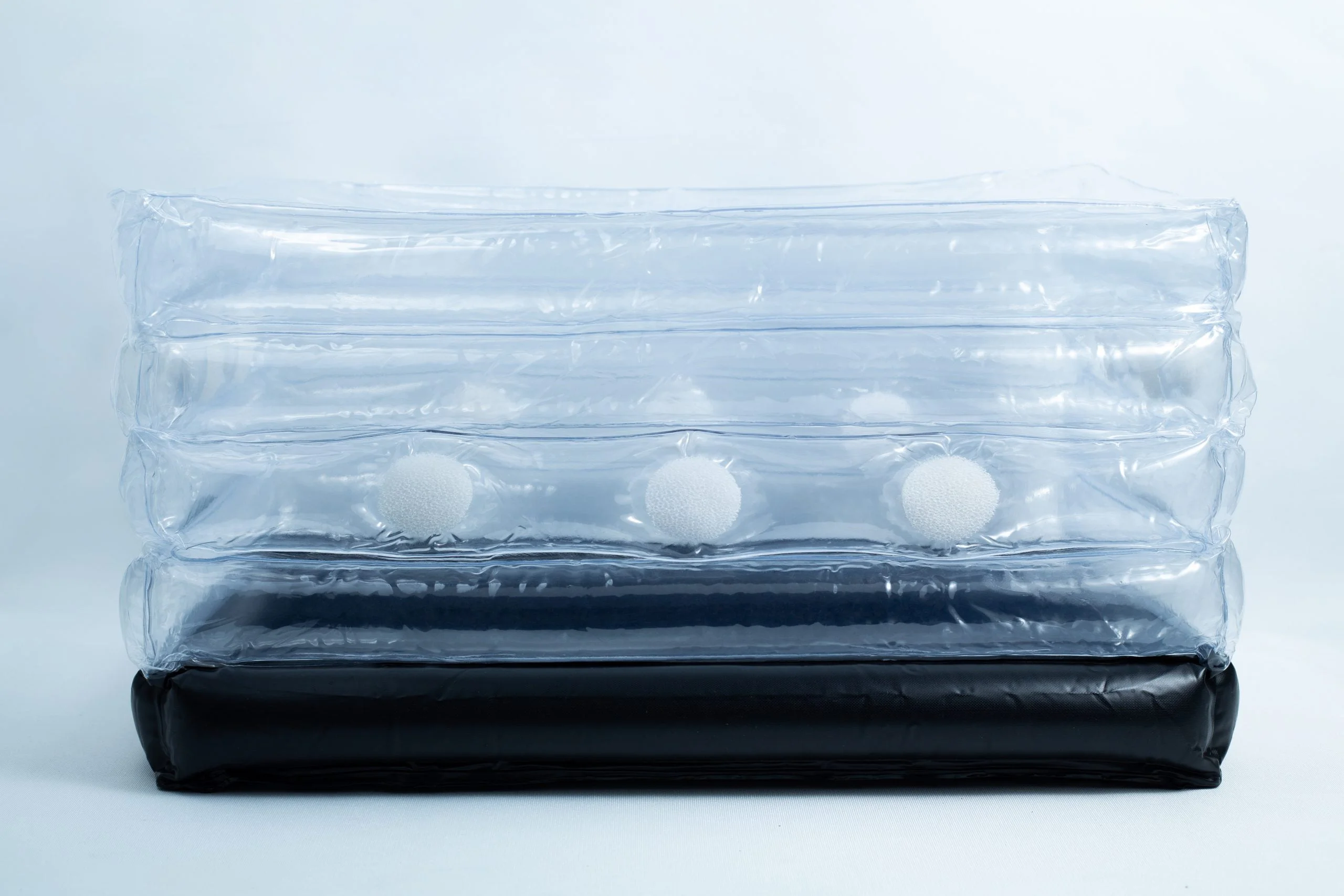 Clear inflatable plastic packaging with white foam balls inside and a black base, set against a plain background.