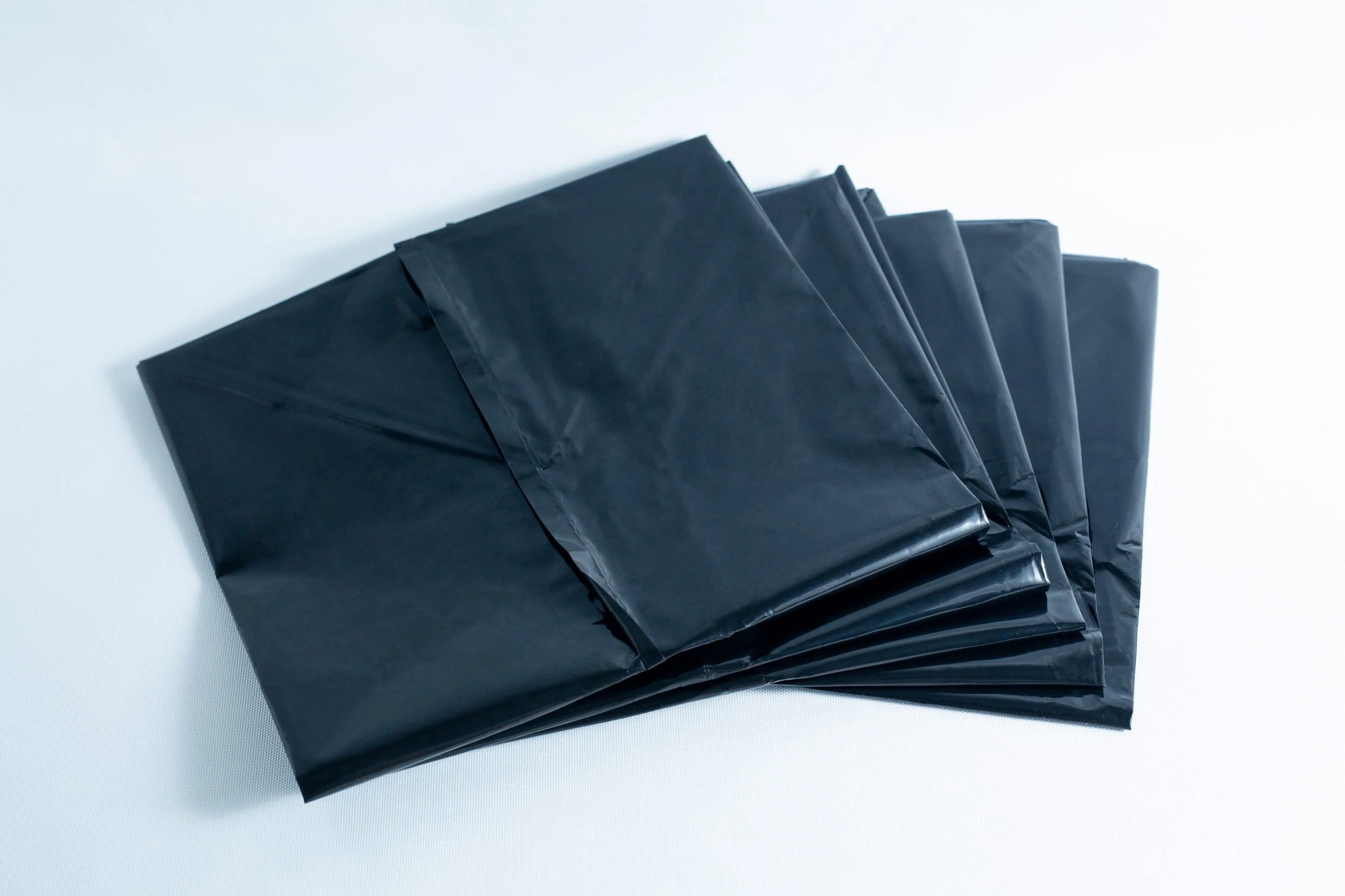 Monotub Mushroom Growing Kit-Premium 13 A stack of black plastic bin bags laid out on a white surface.