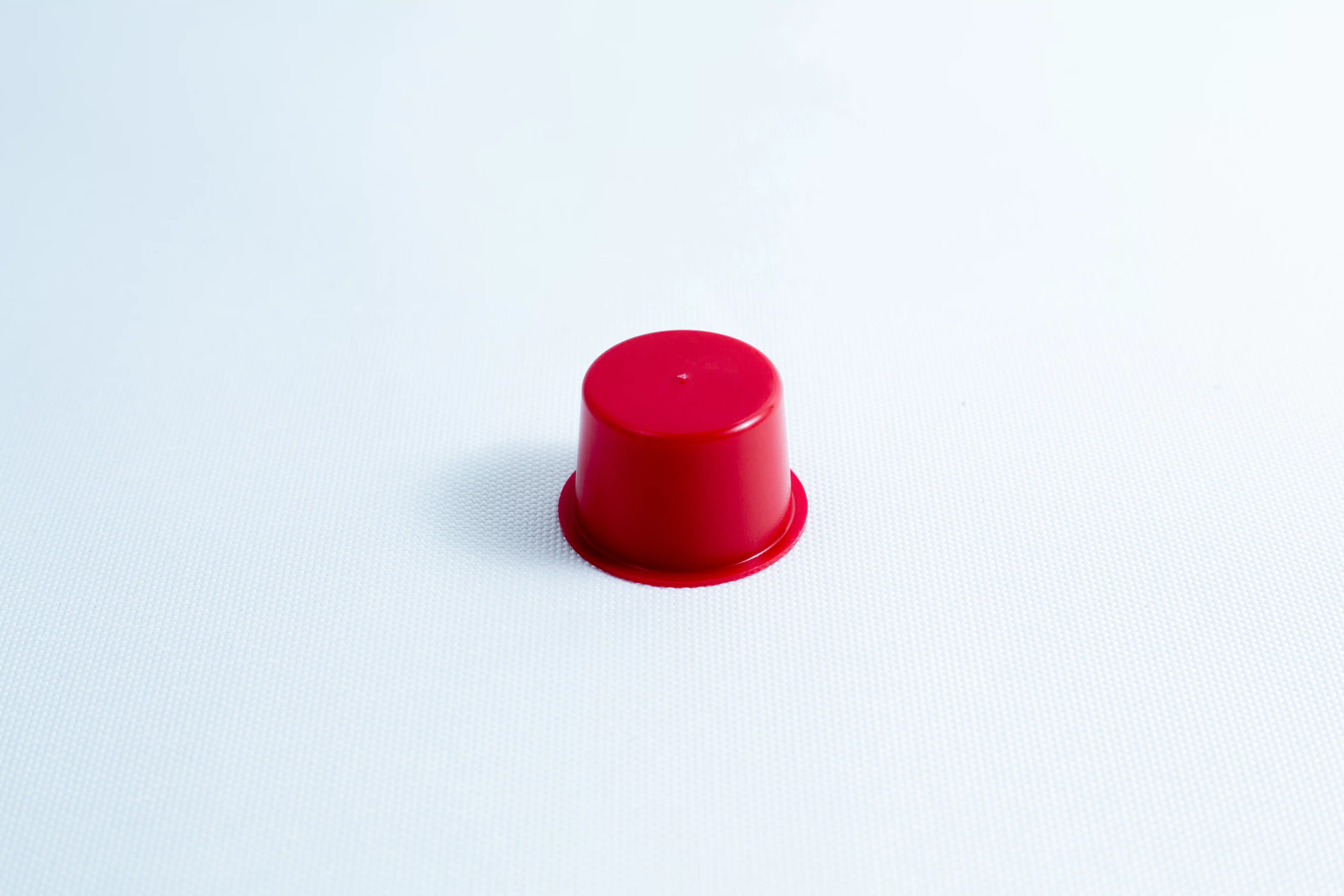 A small red plastic cup turned upside down on a plain white surface.