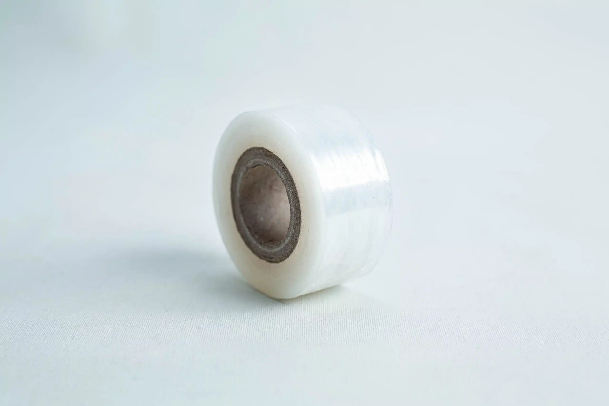 A small roll of Grafting Tape to seal agar plates or for plant grafting, with a brown cardboard core, rests on a light surface.