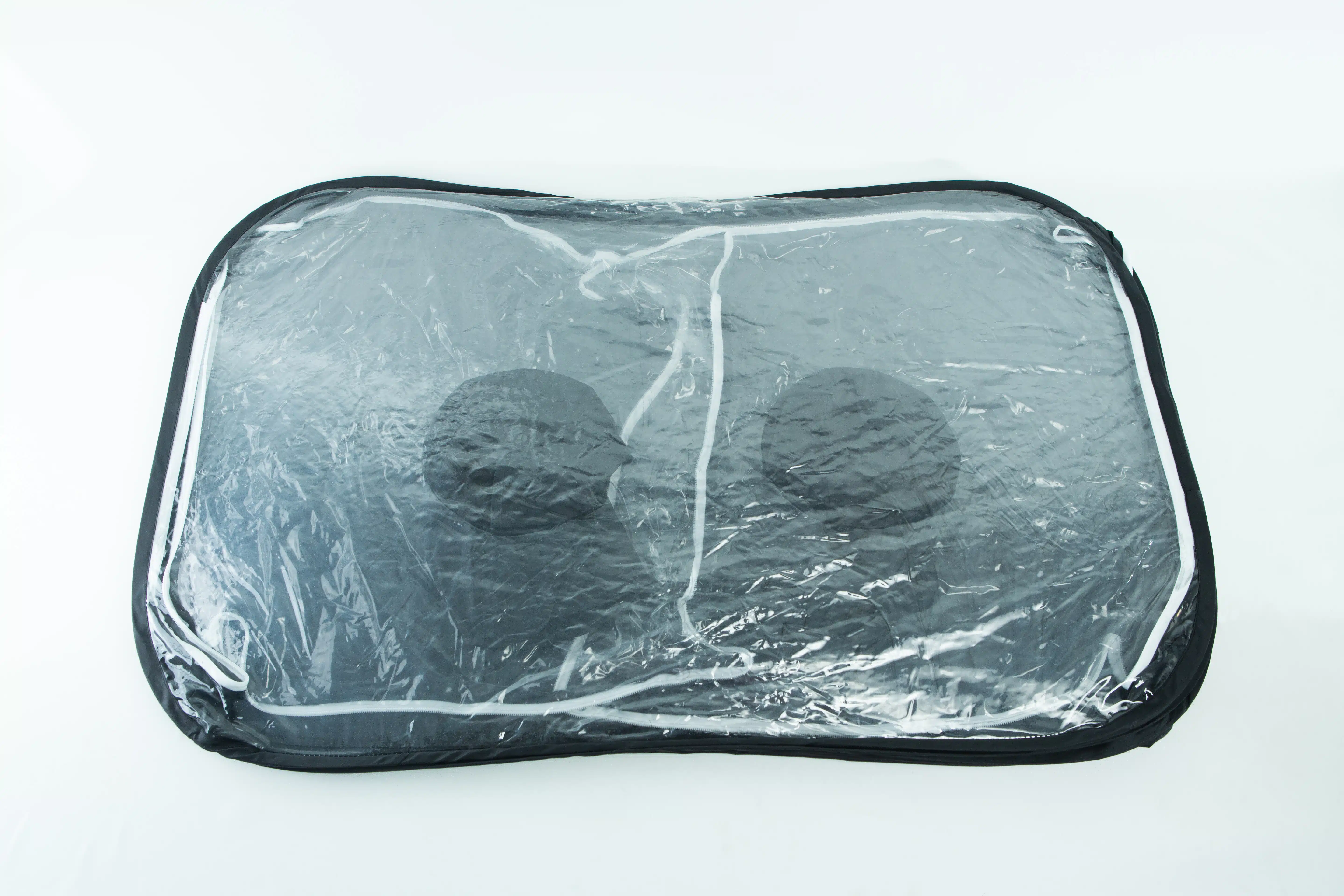 A transparent storage bag with black trim containing two black round objects.