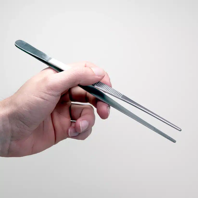 Plant Cell Tissue Culture Starter Kit 8 A hand holds metal tweezers, an essential tool included in the Plant Cell Tissue Culture Starter Kit, set against a plain, light background.