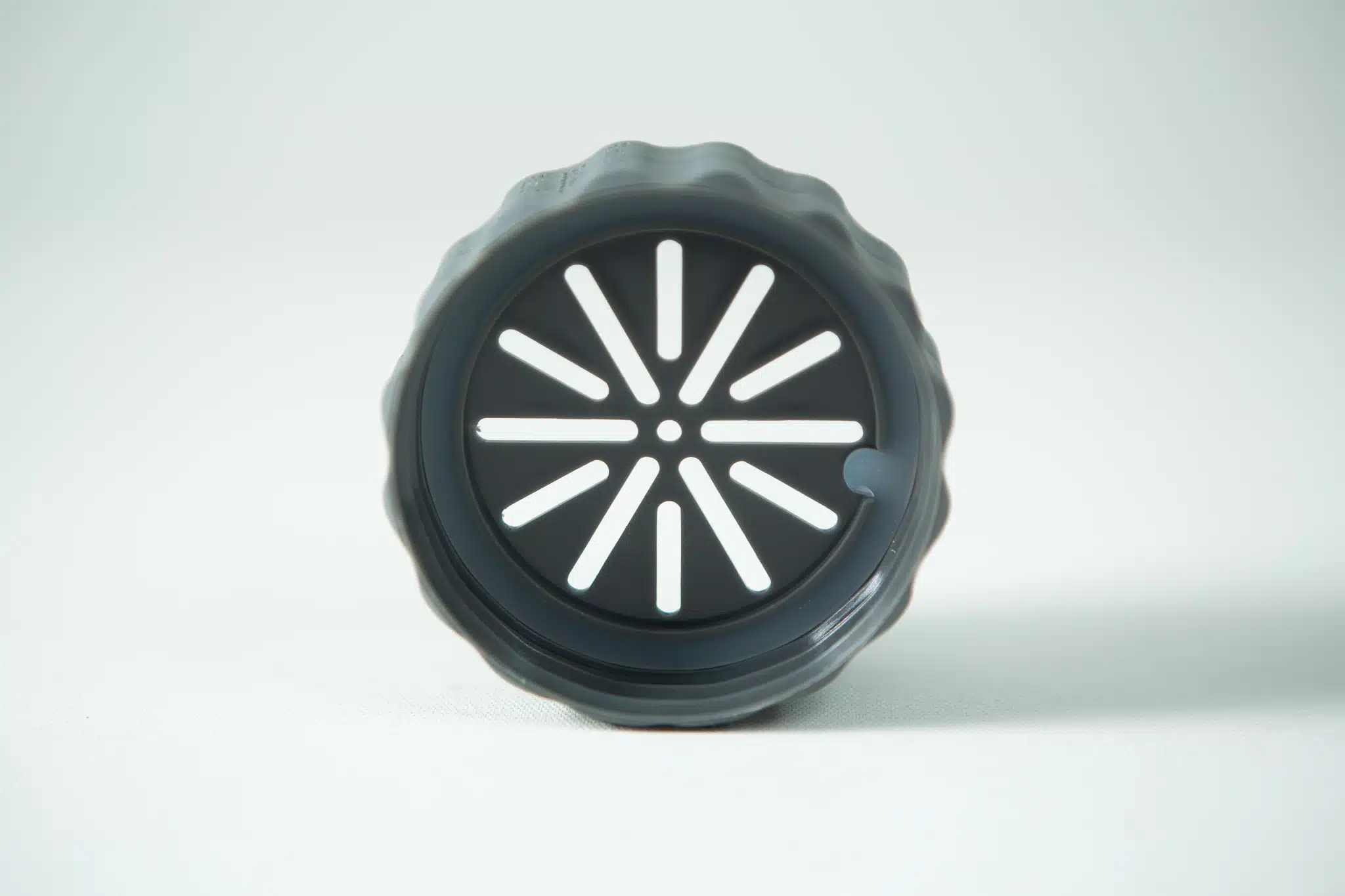 A black round plastic lid with radial slits from the Plant Cell Biocoupler™ Glass Set (16oz, 12oz, 8oz), standing upright on a light surface.