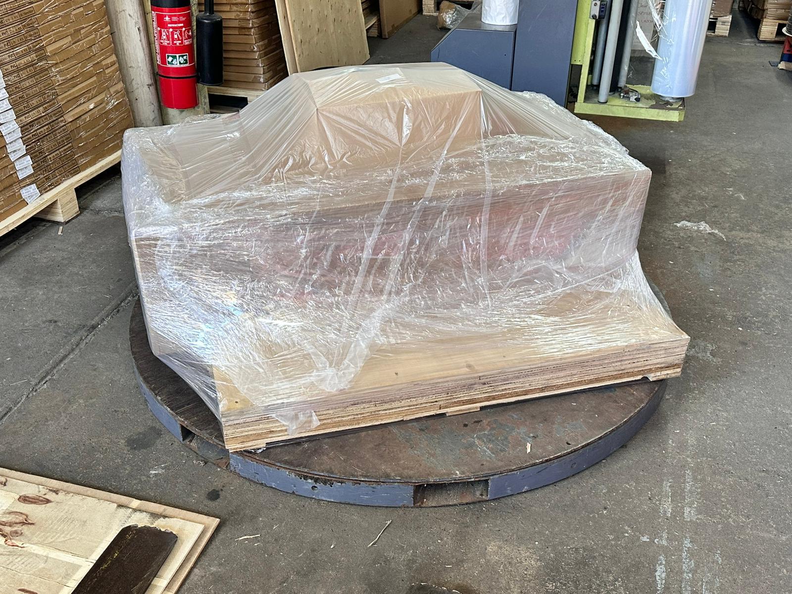 Laminar Flow Hood H14 w/prefilter 120x60x35cm 6 A pallet wrapped in clear plastic sits on a large metal platform in a warehouse, positioned near a Laminar Flow Hood H14 with prefilter 120x60x35cm to ensure optimal air quality.