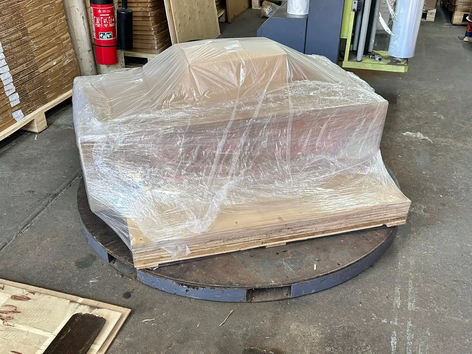 Laminar Flow Hood H14 w/prefilter 120x60x35cm 6 A pallet wrapped in clear plastic sits on a large metal platform in a warehouse, positioned near a Laminar Flow Hood H14 with prefilter 120x60x35cm to ensure optimal air quality.