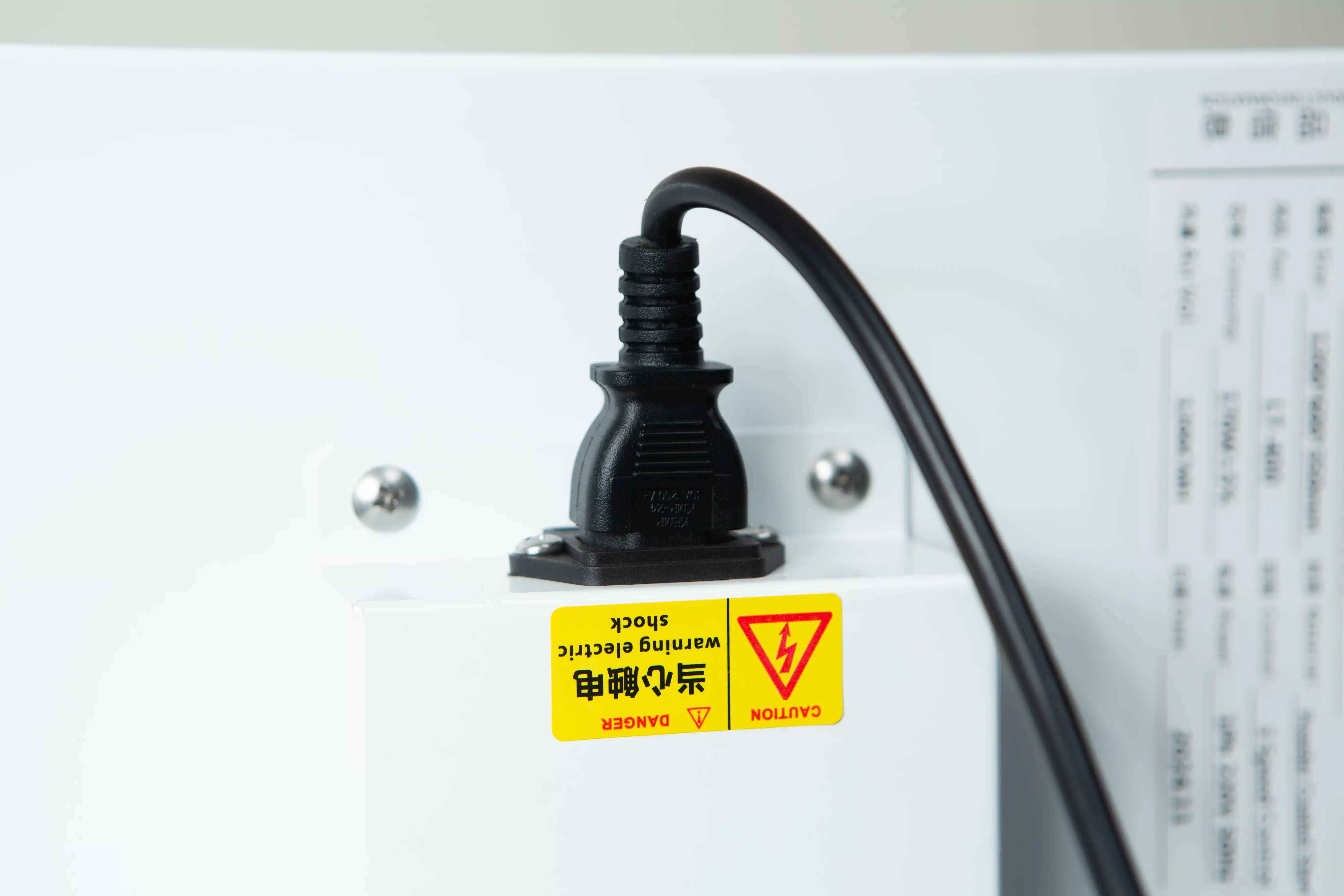 Laminar Flow Hood H14 w/prefilter 120x60x35cm 4 A Laminar Flow Hood H14 with prefilter (120x60x35cm) is plugged in with a black power lead to a white socket featuring an English and Chinese yellow electric shock warning label.