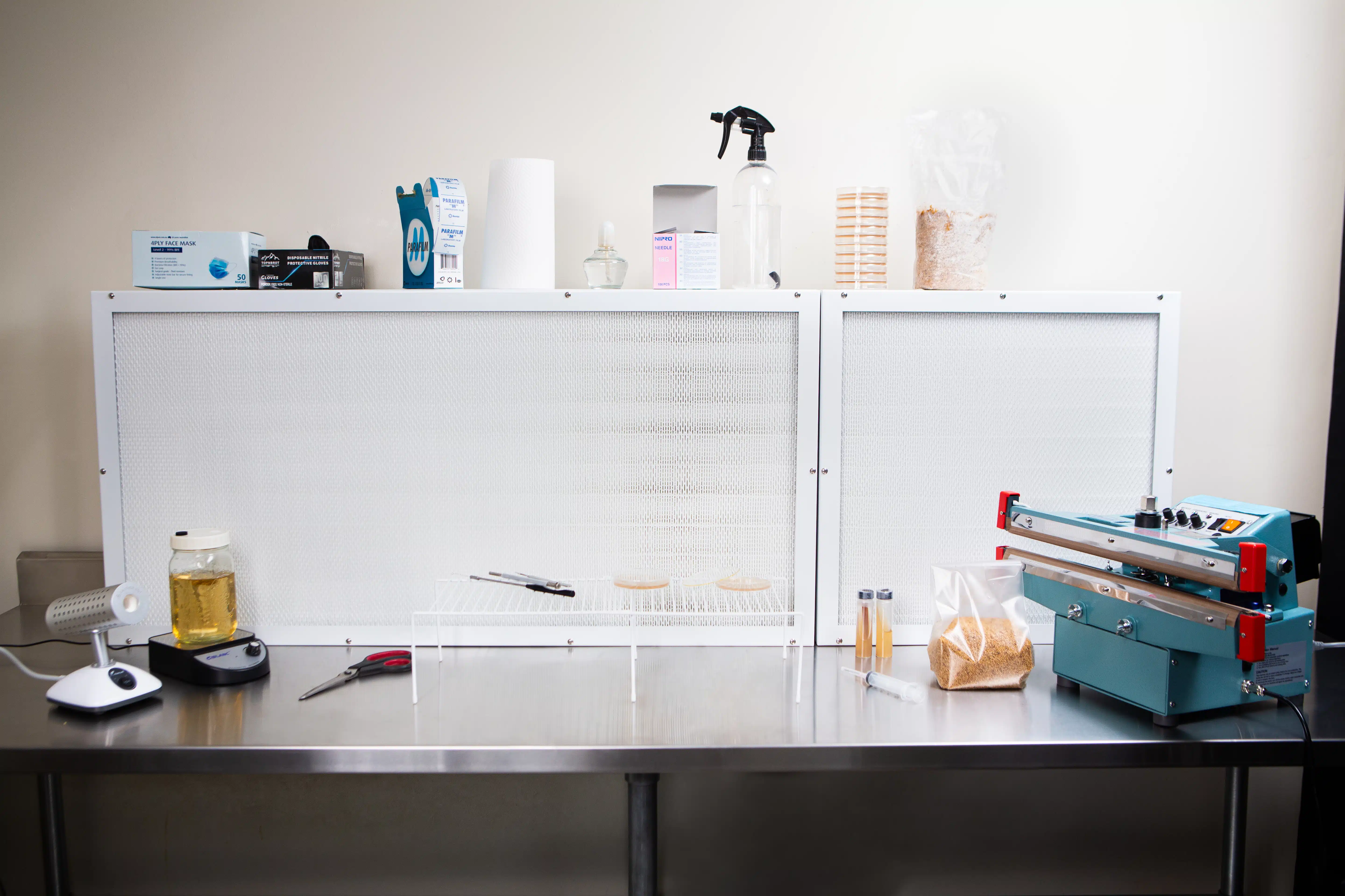 Laminar Flow Hood H14 w/prefilter 120x60x35cm 5 The Laminar Flow Hood H14 with prefilter (120x60x35cm) provides a sterile lab workbench, ideal for handling petri dishes, lab tools, and equipment on its metal table.
