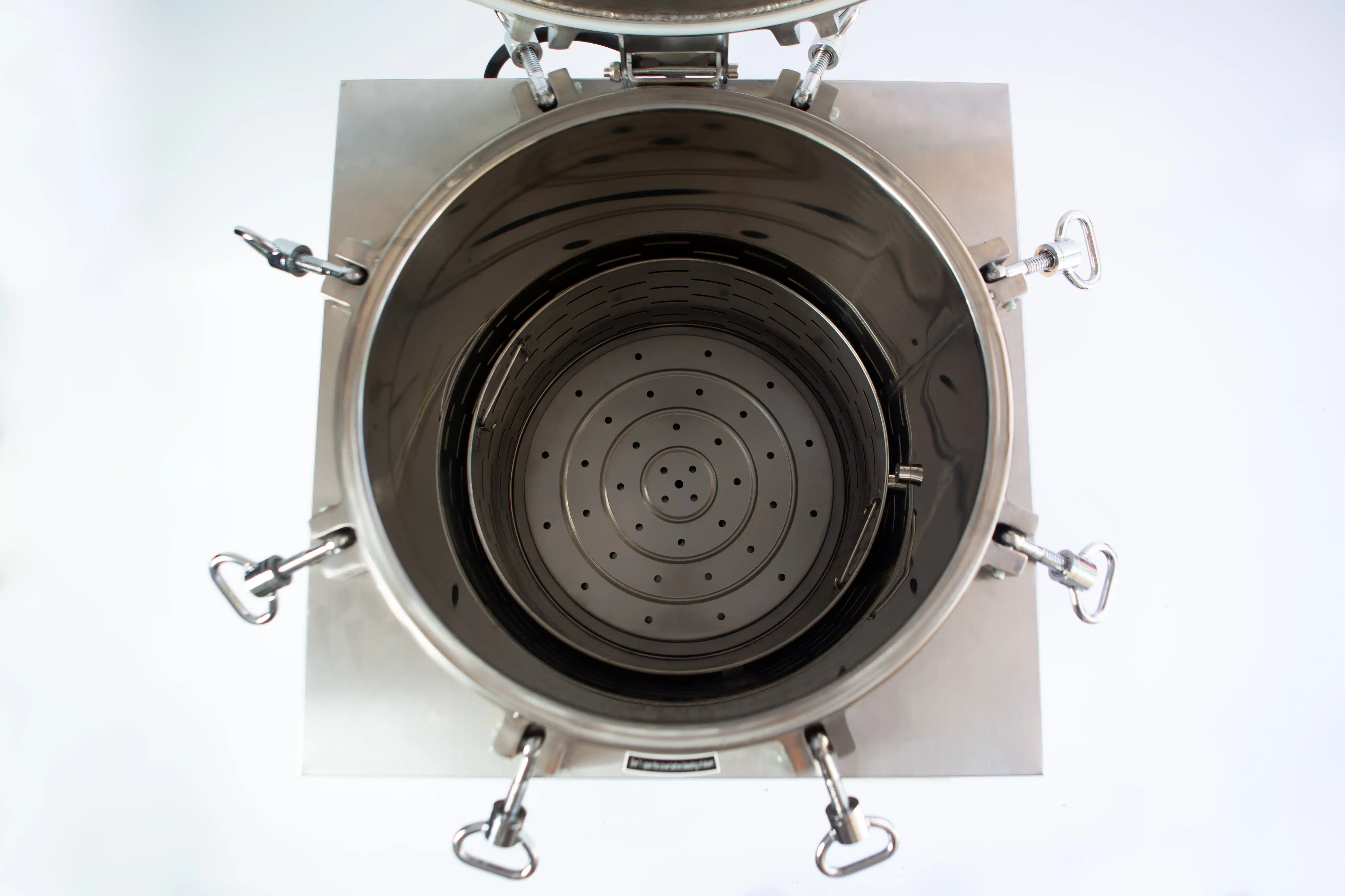Vertical Autoclave 150 Liters (Automatic) | Commercial use | 6KW 9 Top view of an open, empty stainless steel industrial container with clamps and a perforated bottom.