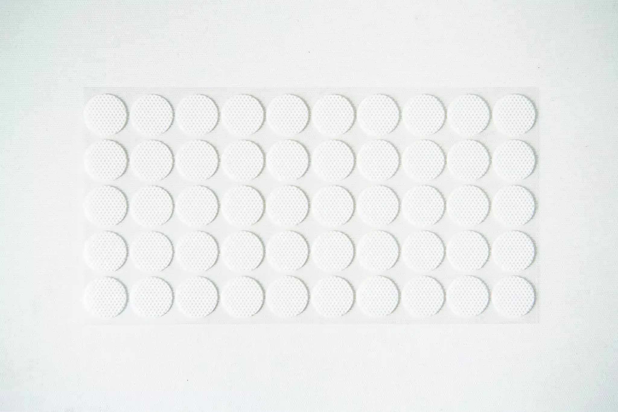 A sheet of small, round, white adhesive stickers arranged in a grid pattern on a white background.
