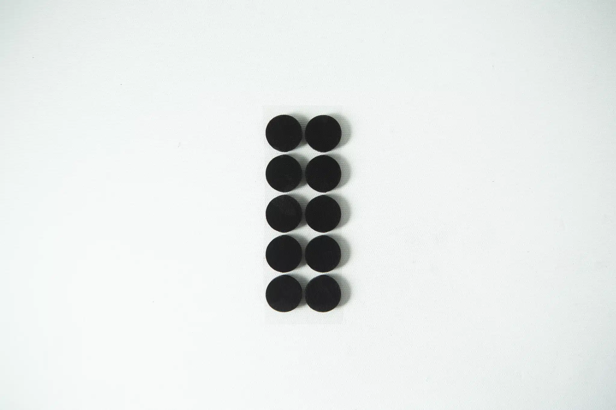 Ten small black circular pads arranged in two columns on a white background.