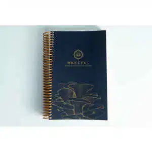 Dark blue spiral-bound Wakeful Mushroom Cultivation Journal by Australian mycologist Caine Barlow, featuring gold mushrooms on the cover.