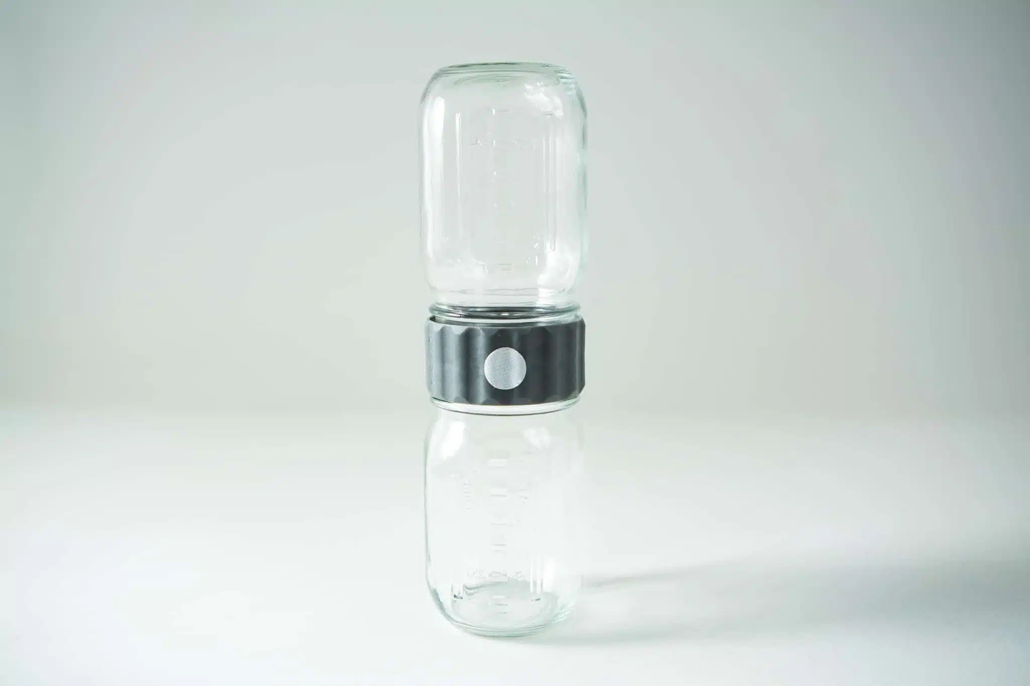Two glass jars are stacked vertically, connected by a black and silver adaptor in the centre.