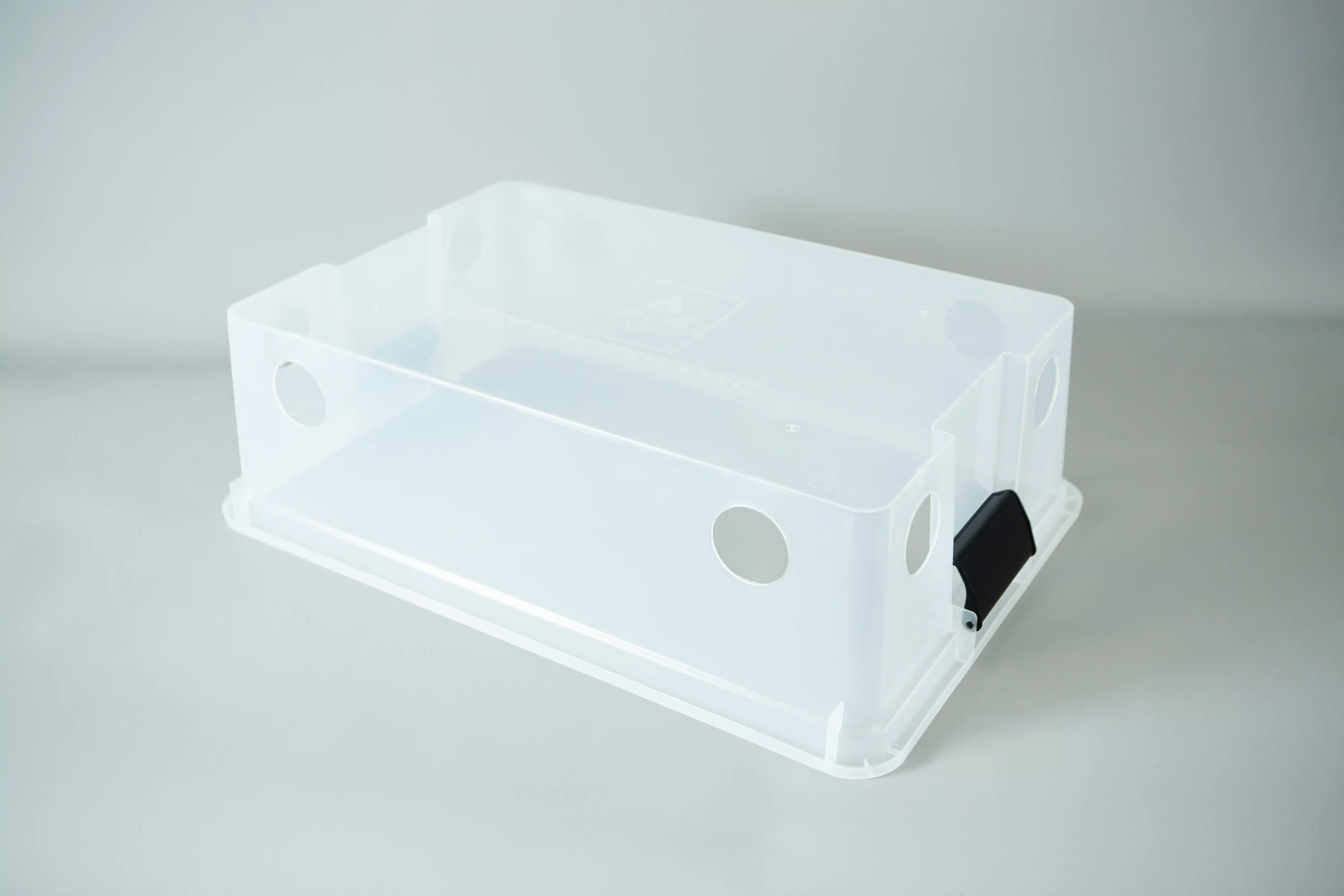 Monotub kit for Growing mushrooms- Max Yield Bins 2 A clear plastic monotub kit with circular holes and a black catch, designed for growing mushrooms, is placed on a light grey surface.