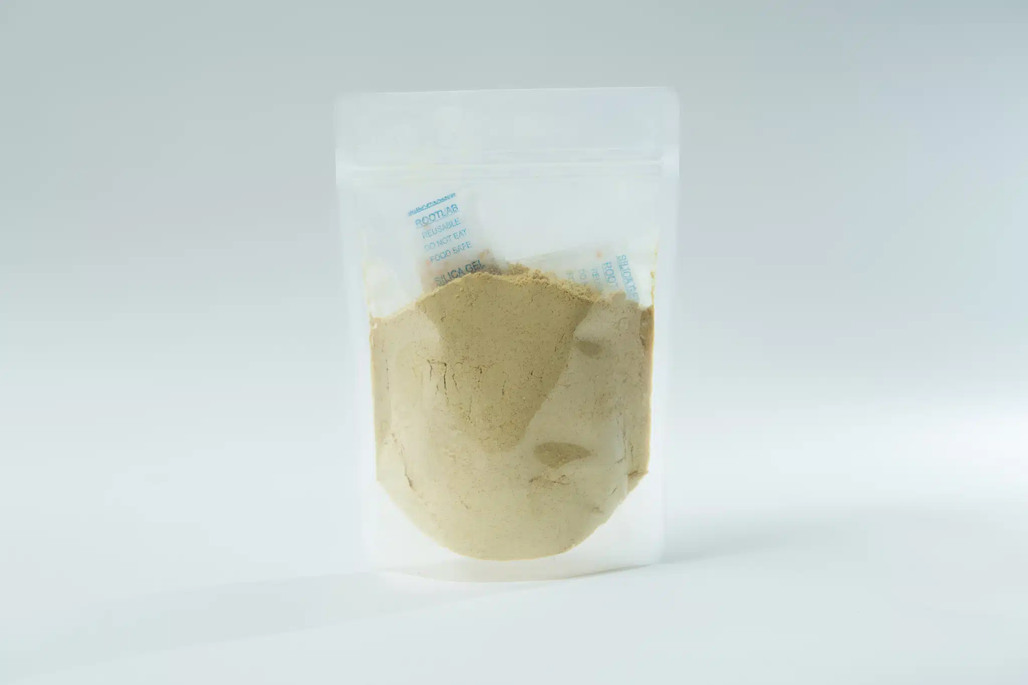 A clear plastic pouch containing light brown Freeze-Dried/ Dehydrated Mushroom Lion's Mane powder with a small silica gel sachet inside.