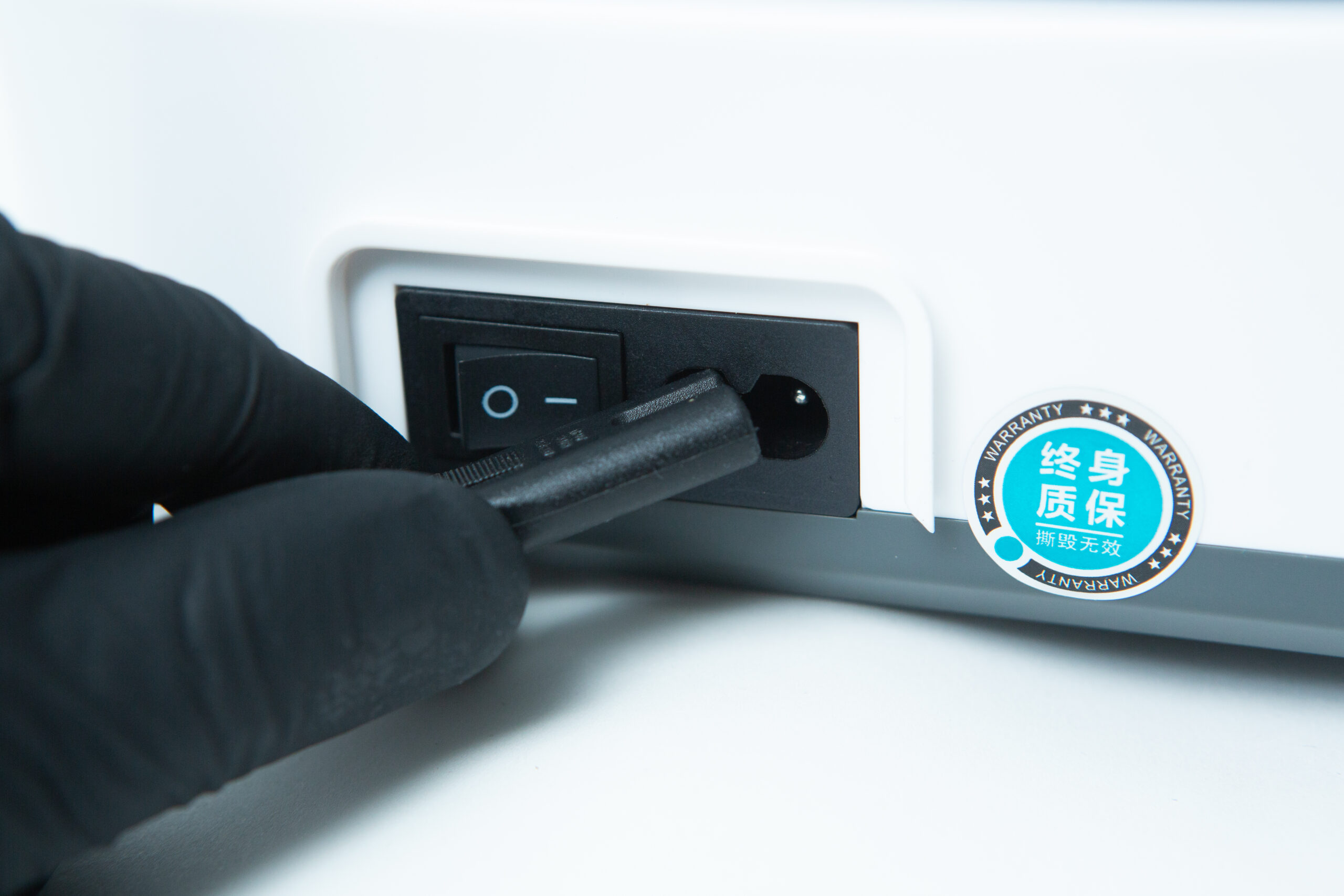 Laboratory Orbital Shaker | 200RPM | 220V | AU Plug 7 A gloved hand plugs a power lead into a device with an on/off switch and a warranty sticker.