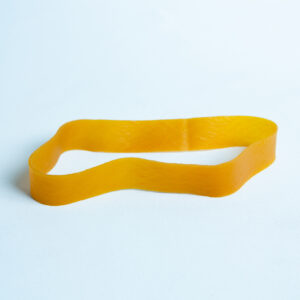 A single yellow elastic band lies flat on a light blue surface.