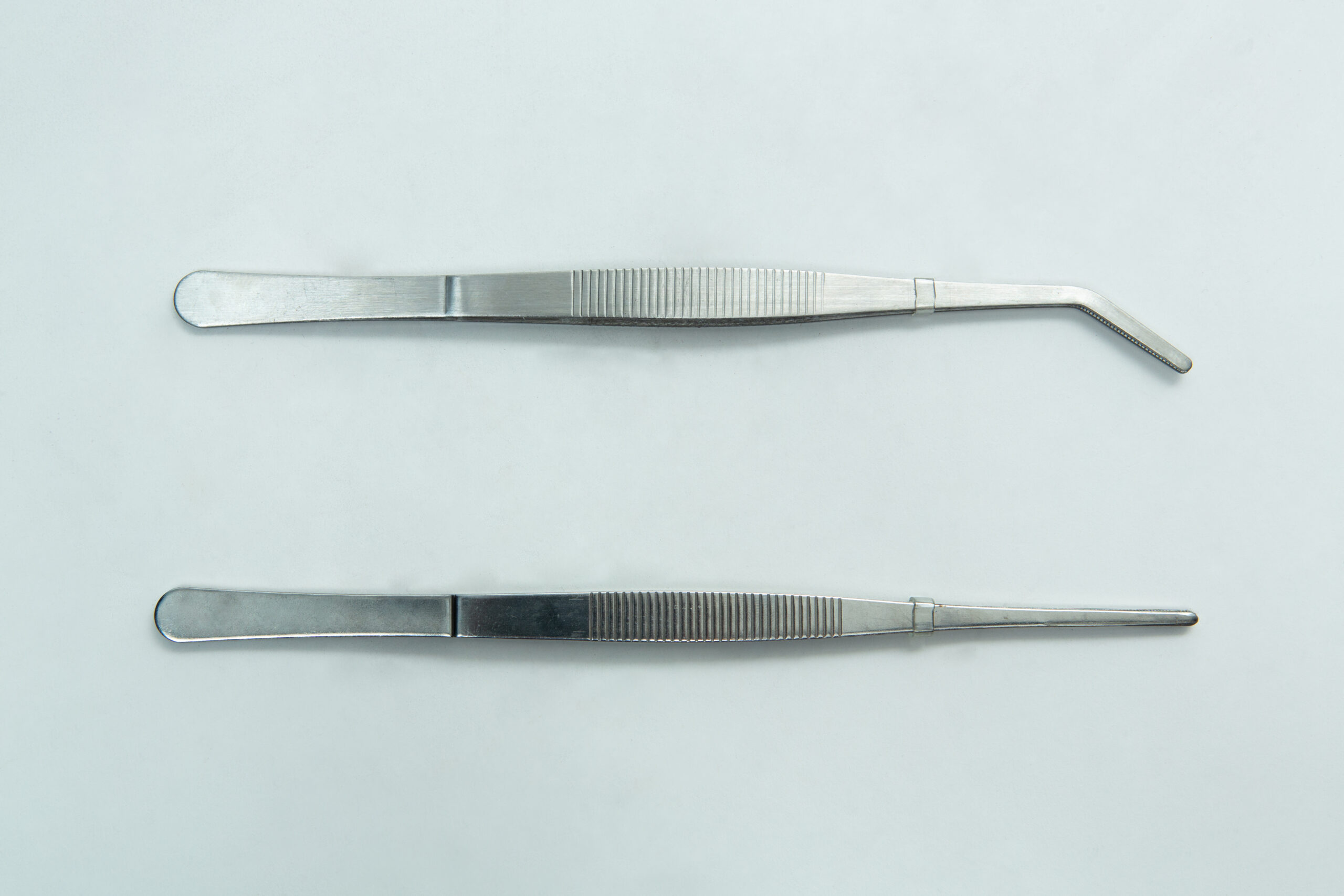 Stainless Steel Plant tissue culture Lab Forceps | Curved & Straight Tips | 15cm 1 Two metal tweezers, one with a curved tip and one with a straight tip, on a plain light background.